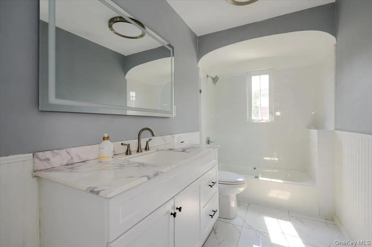 Dual vanity with a stone countertop, an integrated sink, and an expansive wall mirror Dual vanity with a stone countertop, an integrated sink, and an expansive wall mirror