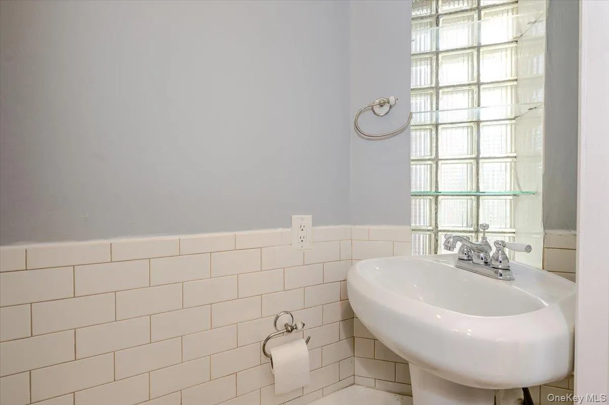 Pedestal sink with chrome fixtures, glass block window, and white subway tile wainscoting Pedestal sink with chrome fixtures, glass block window, and white subway tile wainscoting