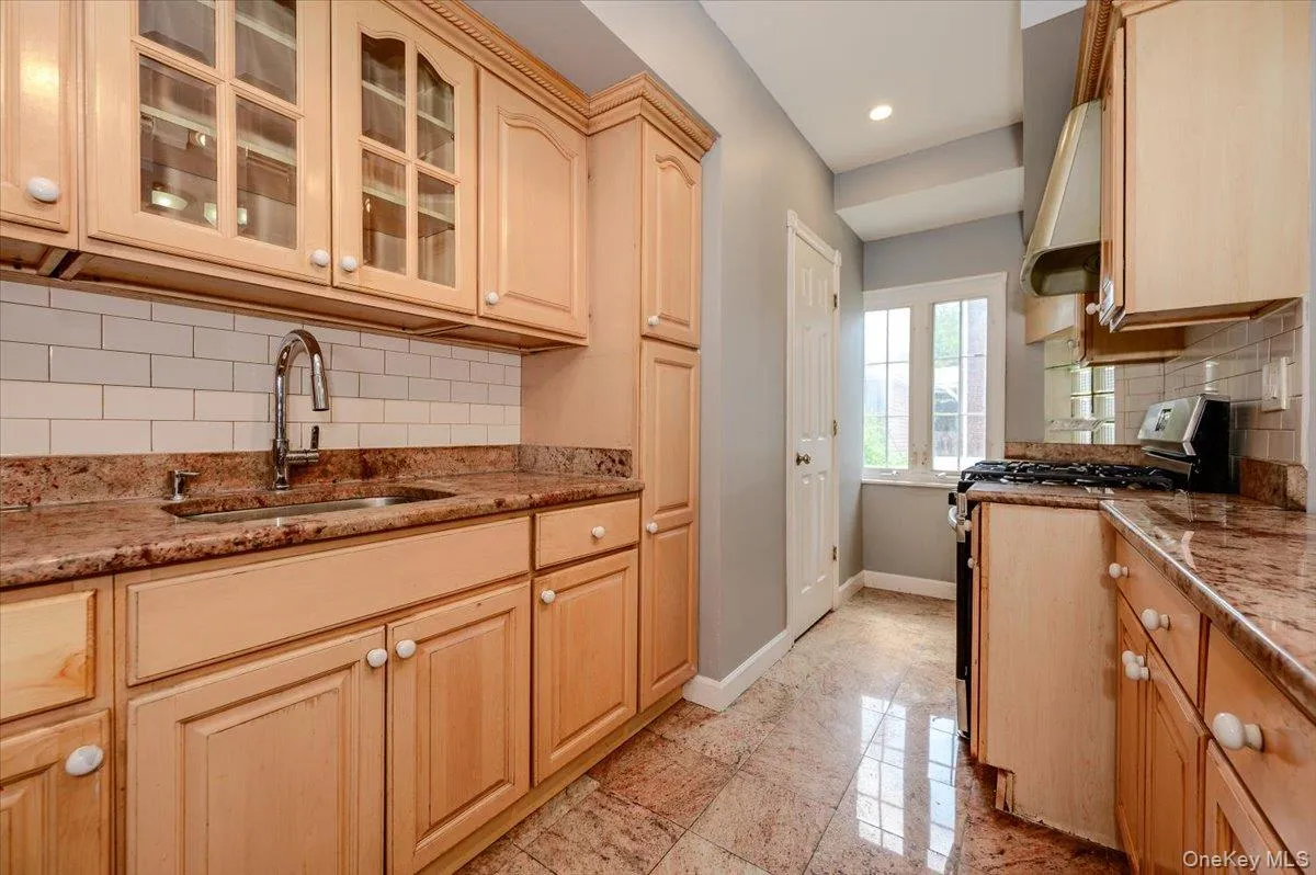 Kitchen featuring wood cabinetry, stone countertops, subway tile backsplash, and a gas range Kitchen featuring wood cabinetry, stone countertops, subway tile backsplash, and a gas range
