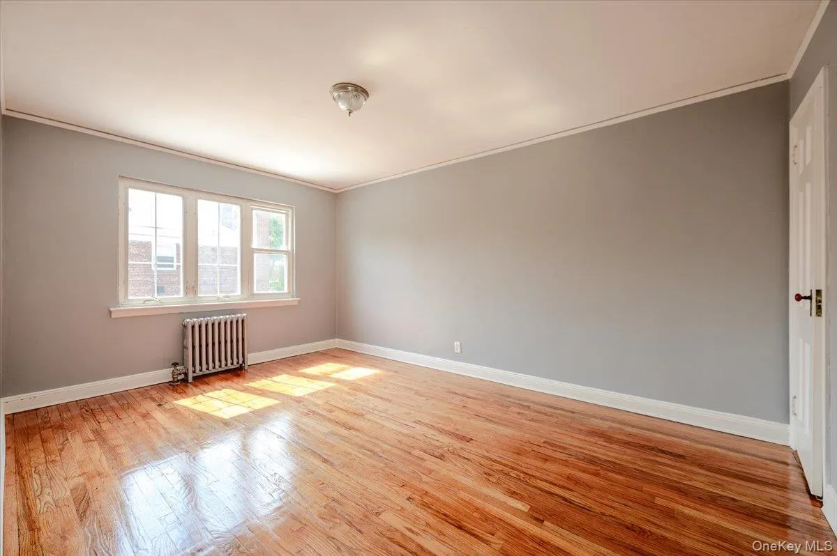 Hardwood flooring with a glossy finish, neutral wall paint, white trim, and a multi-pane window Hardwood flooring with a glossy finish, neutral wall paint, white trim, and a multi-pane window