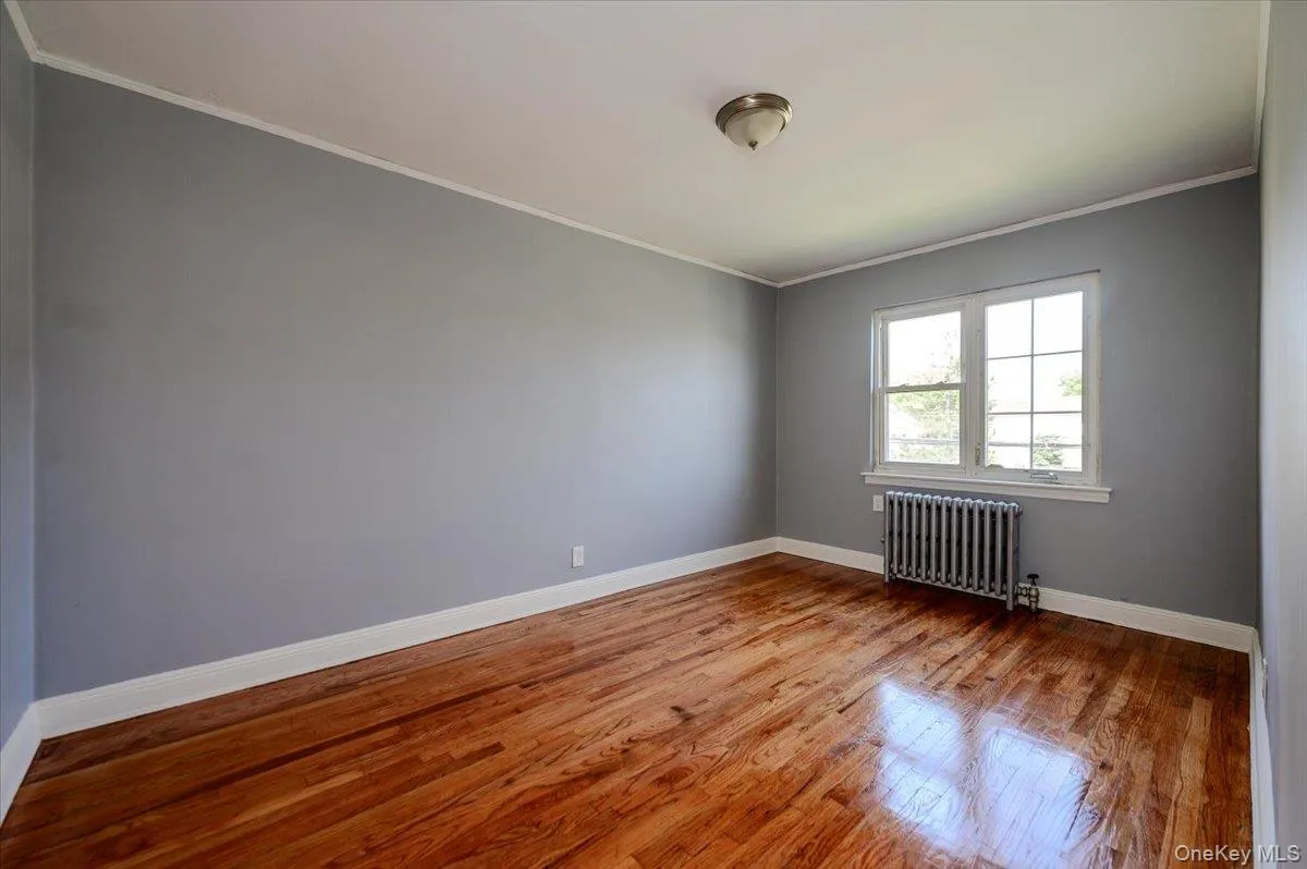 Hardwood flooring, painted walls, window with grilles, and a ceiling-mounted light fixture Hardwood flooring, painted walls, window with grilles, and a ceiling-mounted light fixture