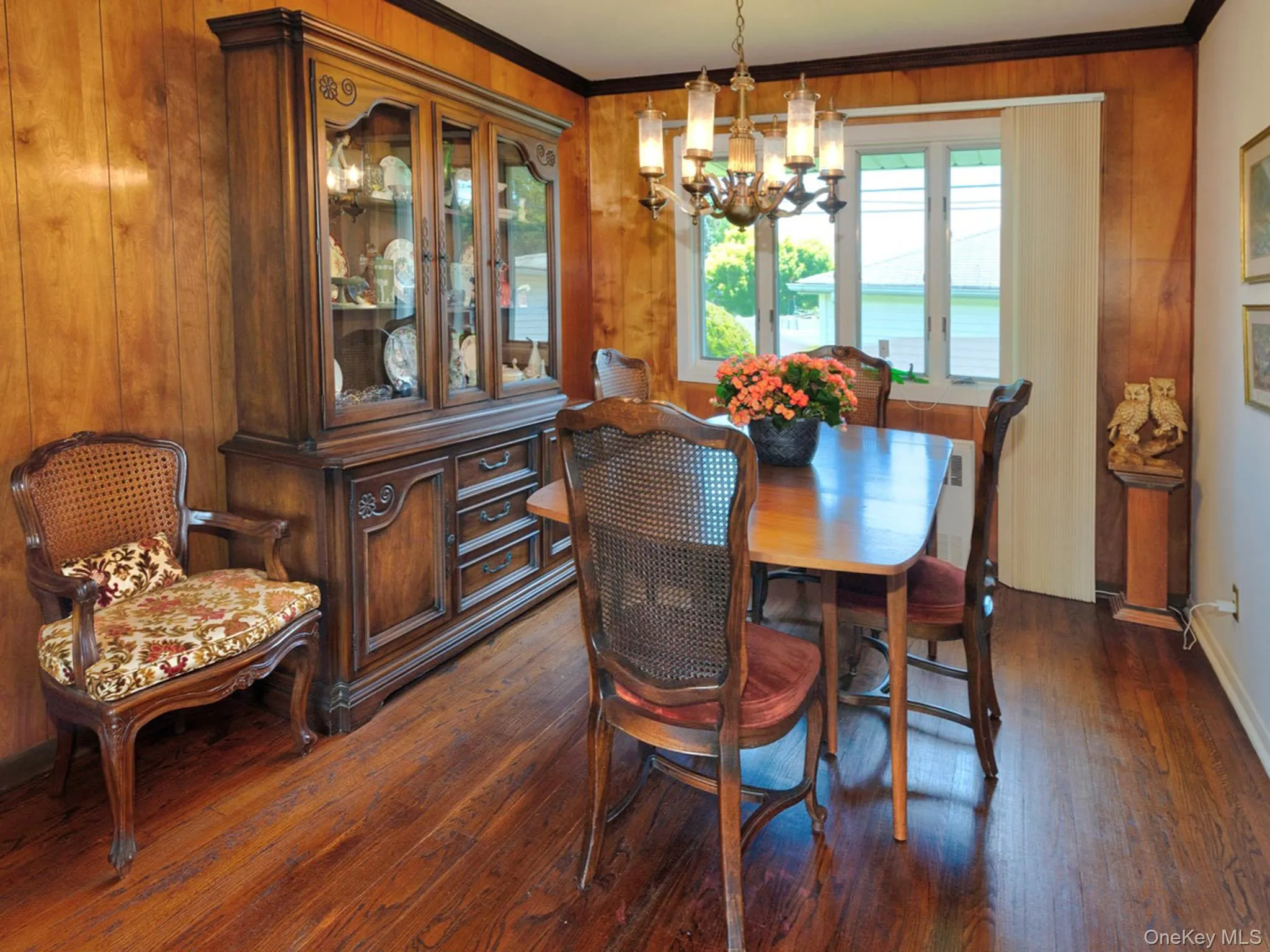 Dining space featuring wood-finish flooring, wood paneling, and a multi-pane window Dining space featuring wood-finish flooring, wood paneling, and a multi-pane window