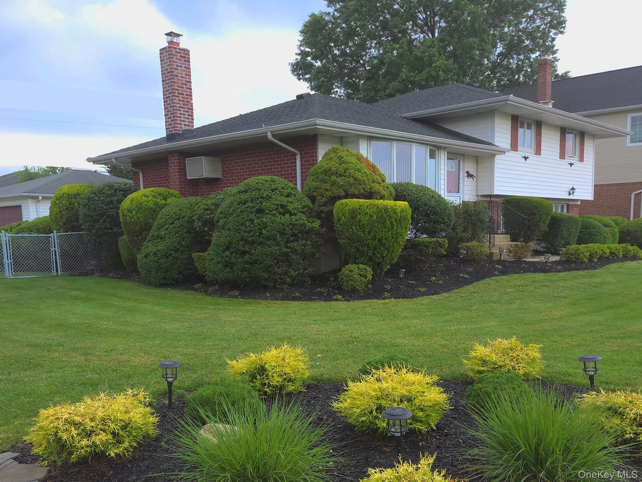 Split-level residence featuring white siding, a dark shingle roof, and a red front door roof Split-level residence featuring white siding, a dark shingle roof, and a red front door roof