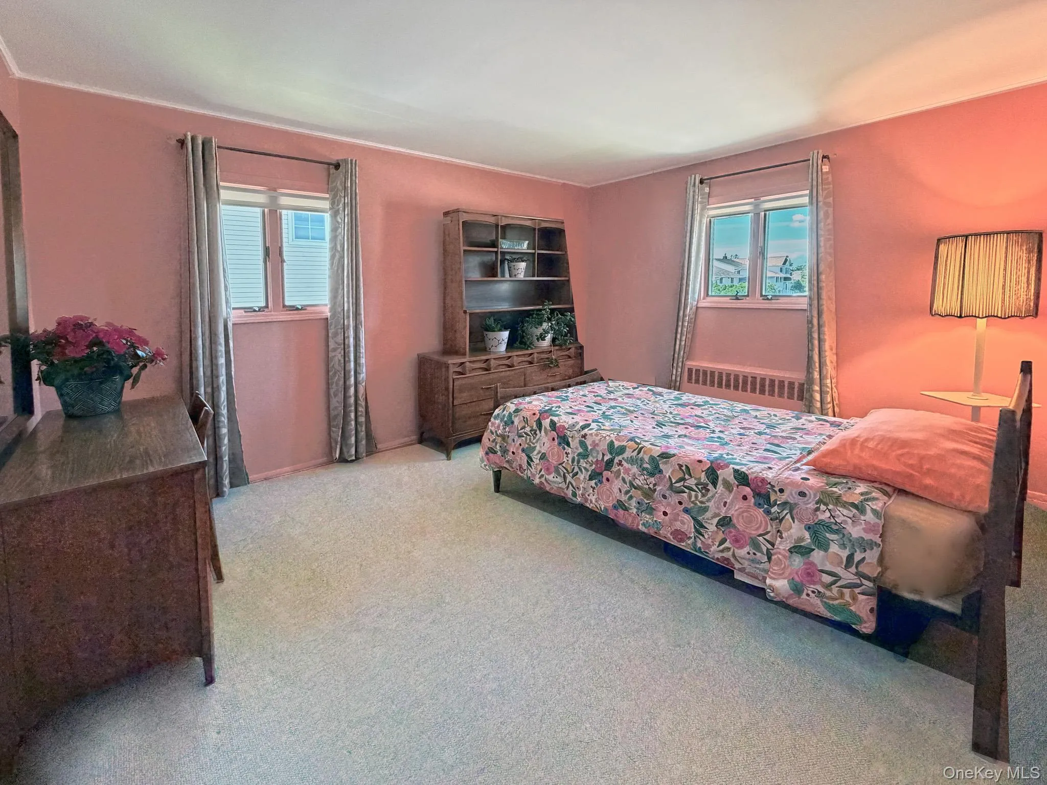 Carpeted room with two windows featuring blinds and drapes, and painted walls Carpeted room with two windows featuring blinds and drapes, and painted walls