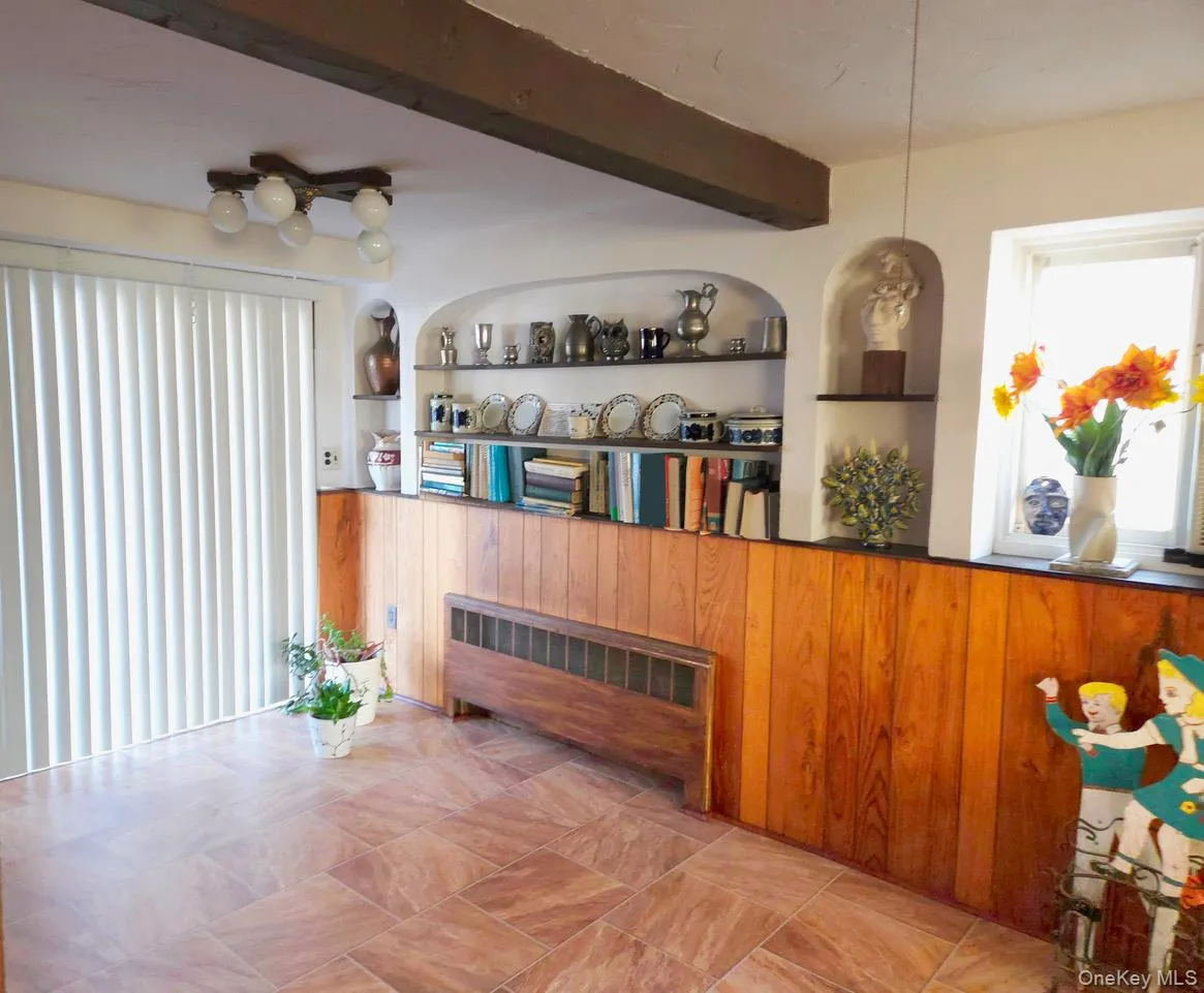 Spacious living area featuring large format tile flooring and wood paneling. Glass sliders to the brick patio and pergola Spacious living area featuring large format tile flooring and wood paneling. Glass sliders to the brick patio and pergola