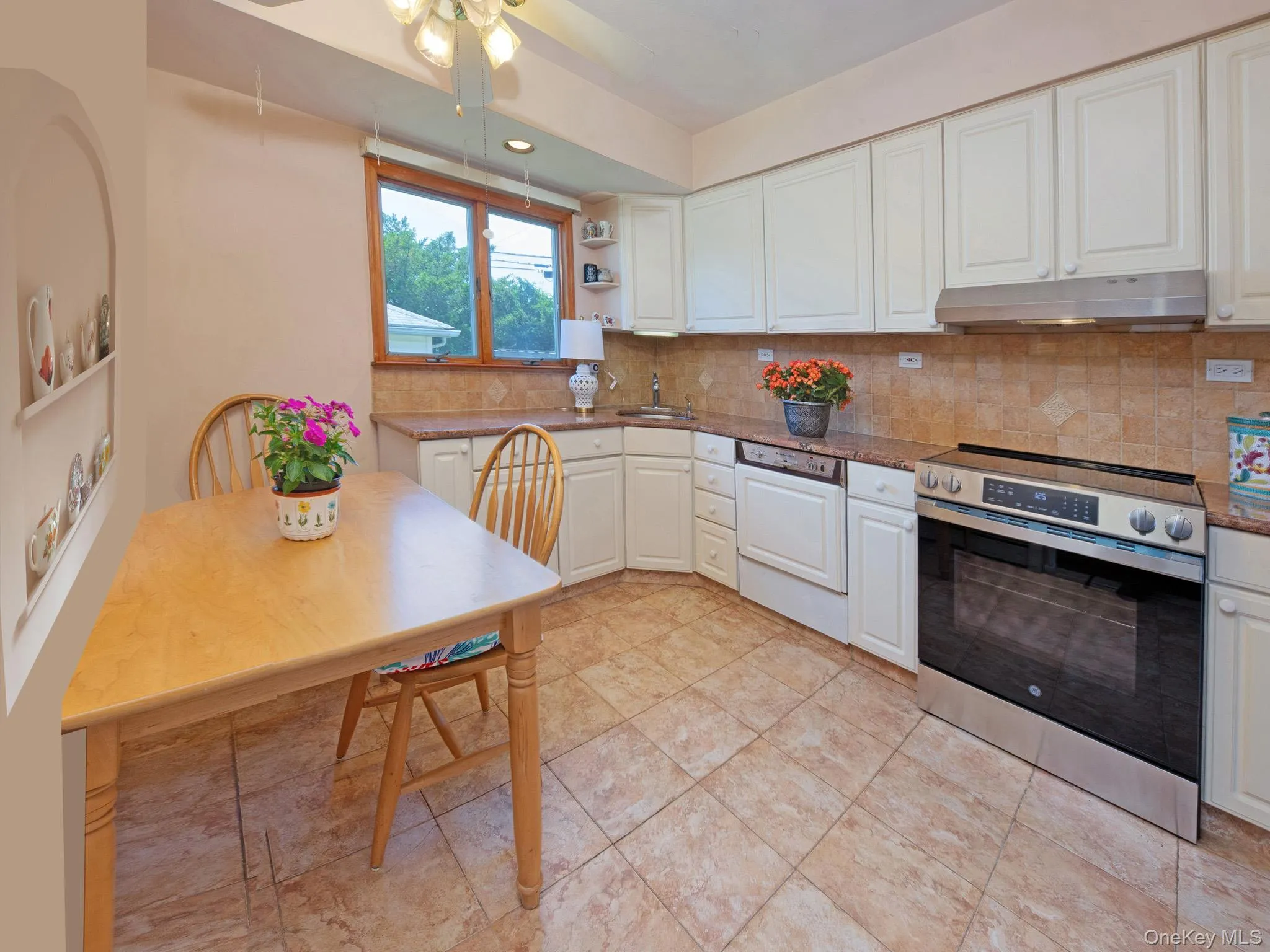 Kitchen featuring white cabinetry, a stainless steel range and hood, granite countertop, tile flooring, and a window Kitchen featuring white cabinetry, a stainless steel range and hood, granite countertop, tile flooring, and a window