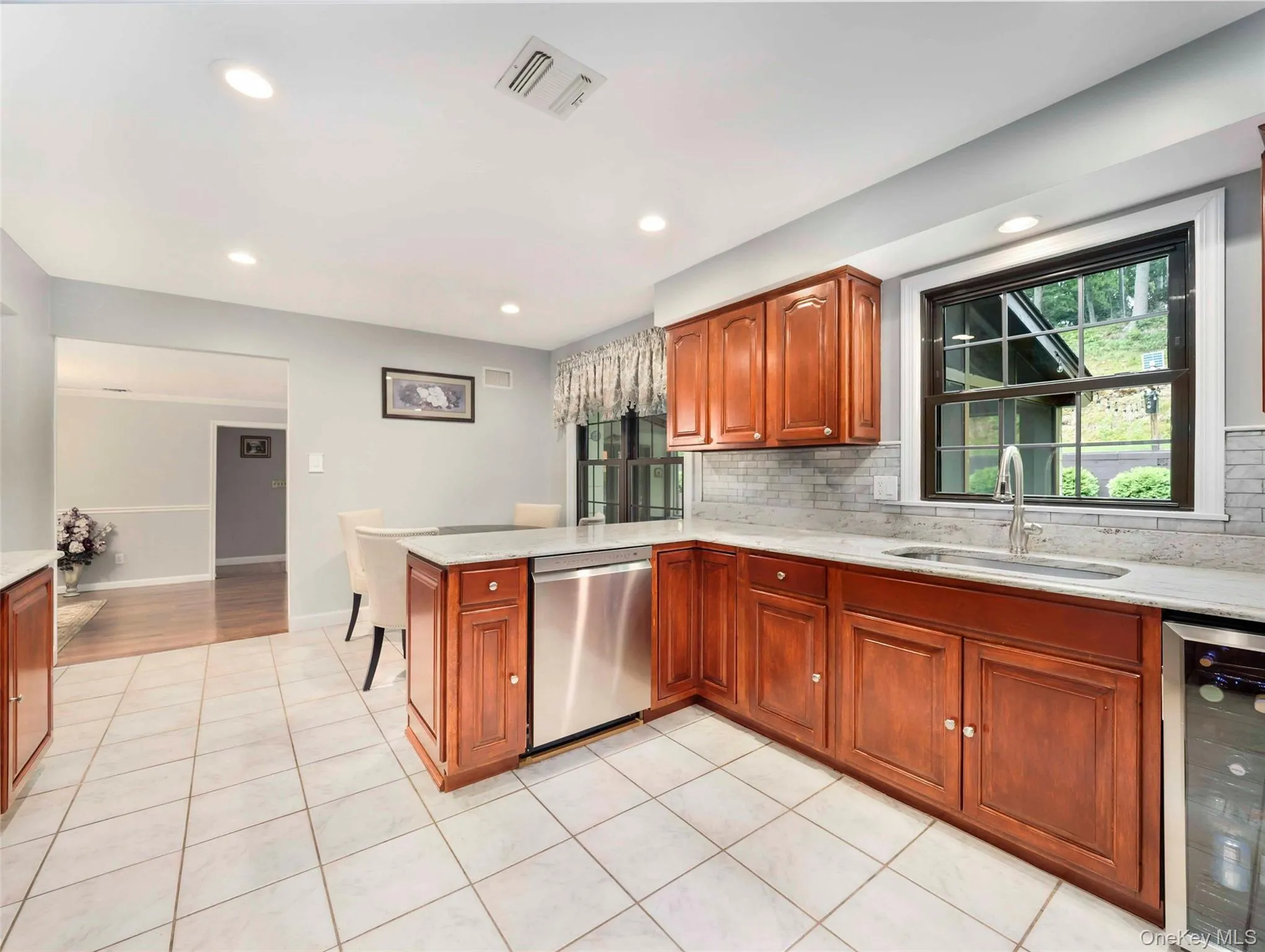 Kitchen featuring tiled flooring, wood cabinetry, stone countertops, a stainless steel dishwasher, and recessed lighting Kitchen featuring tiled flooring, wood cabinetry, stone countertops, a stainless steel dishwasher, and recessed lighting