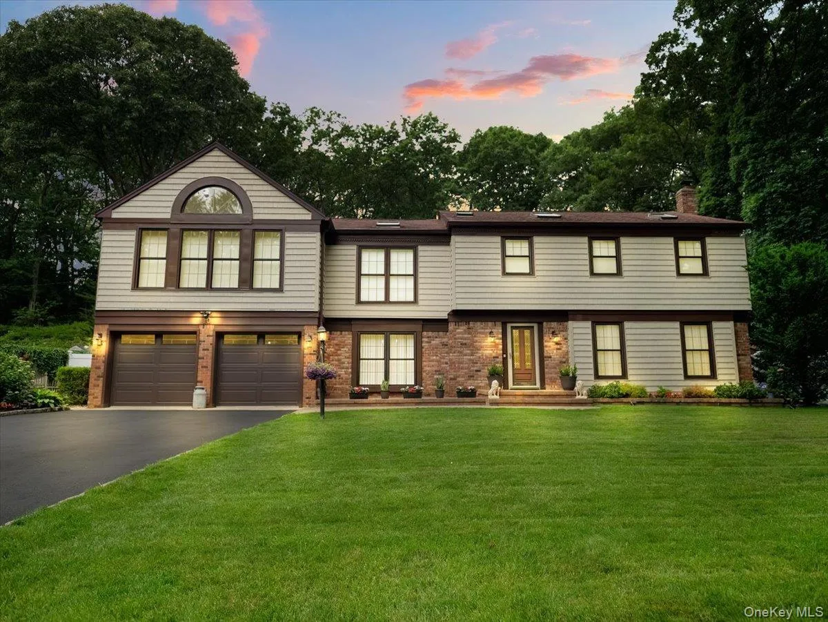 Two-story residence featuring light gray siding, brick accents, and a brown trim Two-story residence featuring light gray siding, brick accents, and a brown trim