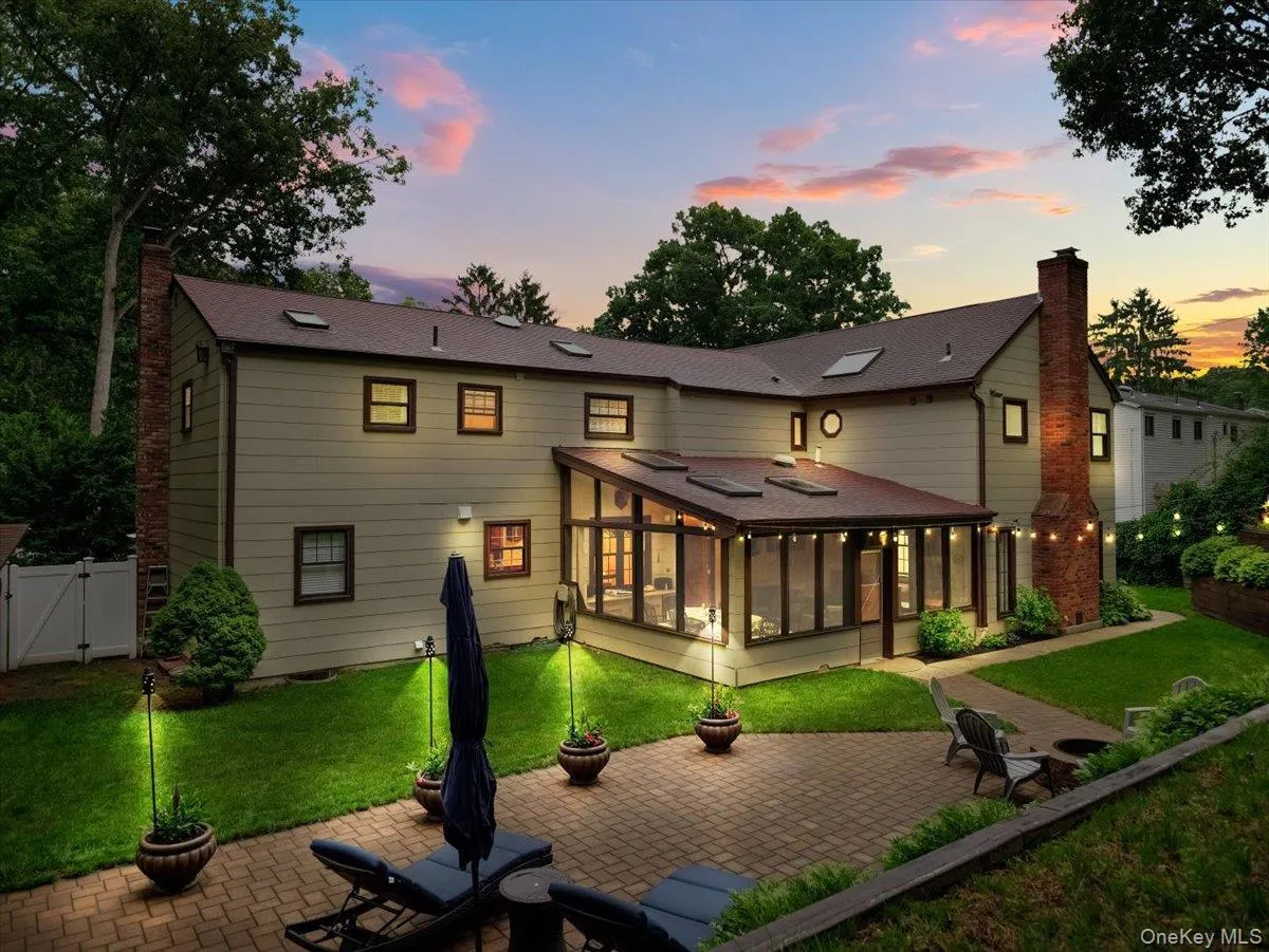 Expansive rear exterior featuring a paved patio and a glass-enclosed sunroom with skylights Expansive rear exterior featuring a paved patio and a glass-enclosed sunroom with skylights