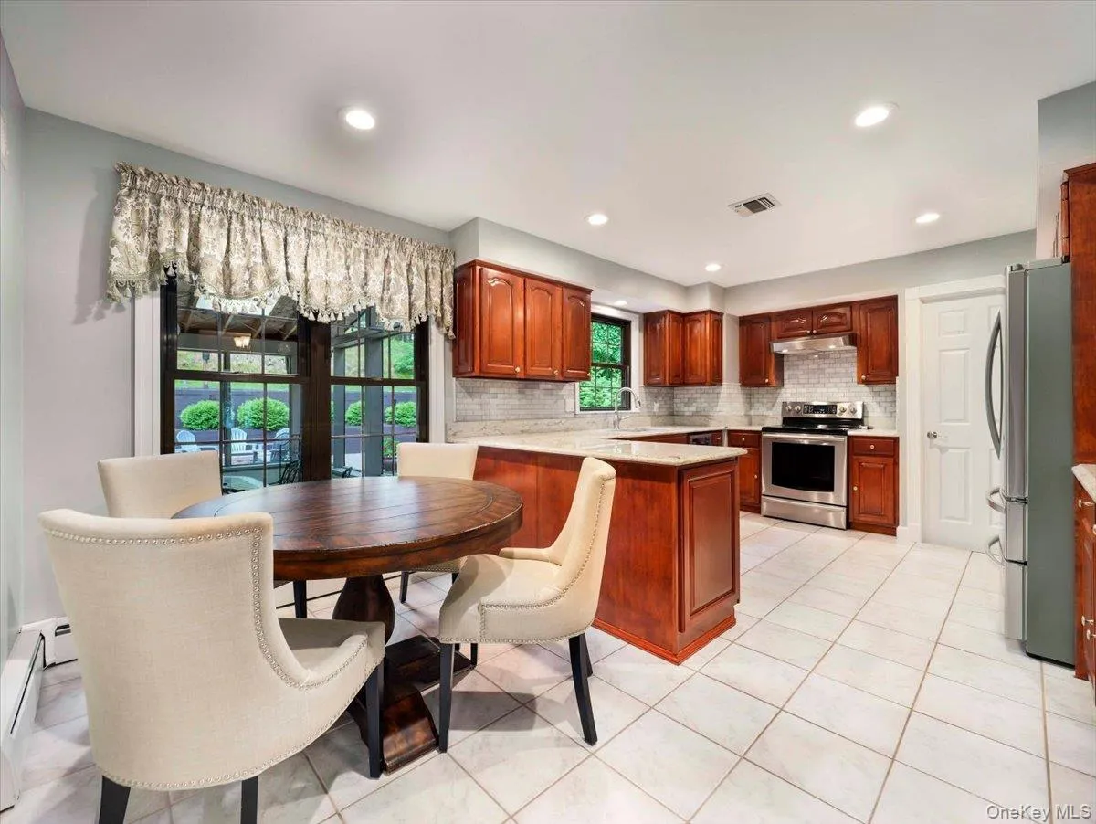 Well-appointed kitchen featuring wood cabinetry, stainless steel appliances, and a tiled backsplash Well-appointed kitchen featuring wood cabinetry, stainless steel appliances, and a tiled backsplash