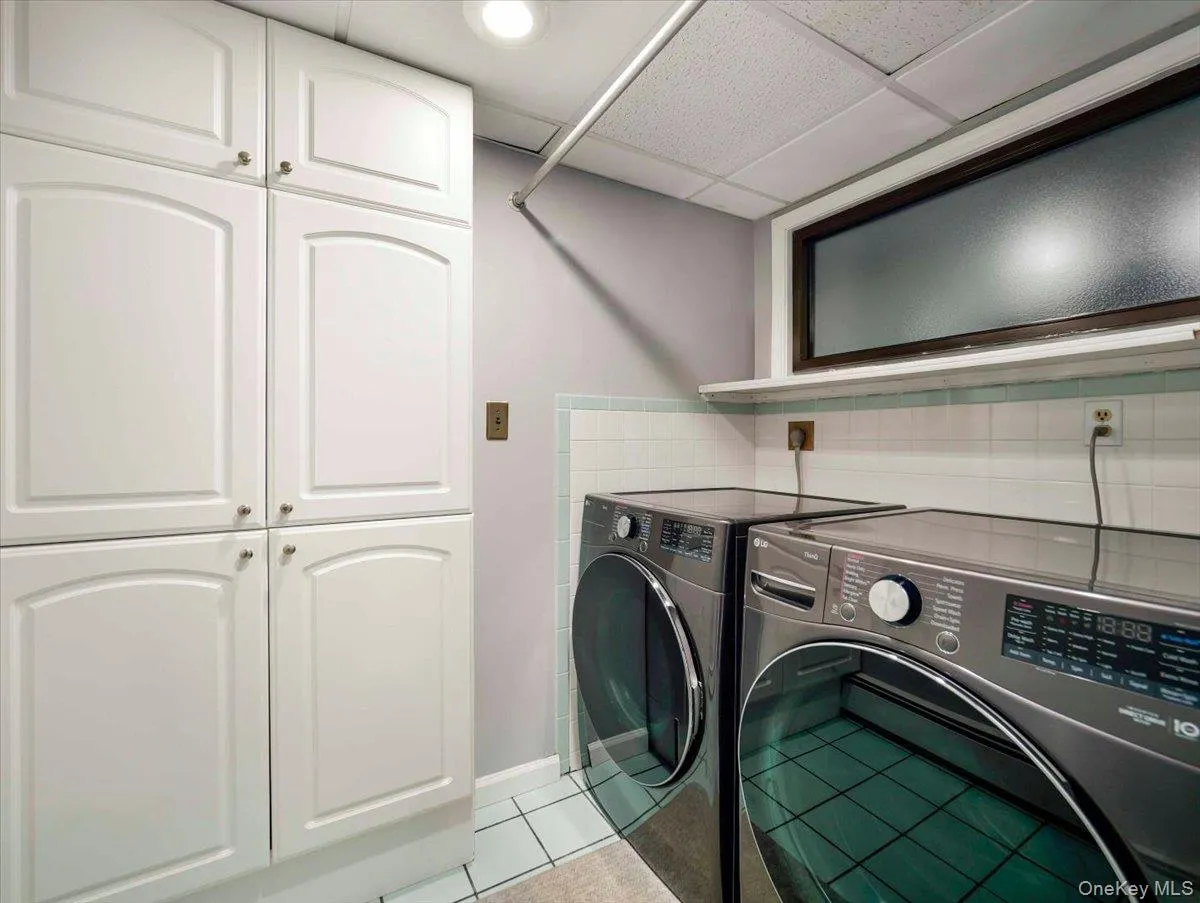 Laundry area with white paneled cabinetry, light blue wall tile, and frosted glass window Laundry area with white paneled cabinetry, light blue wall tile, and frosted glass window