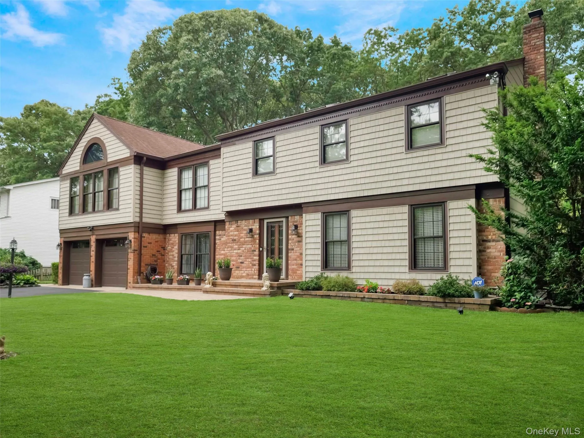 Two-story residence featuring shingle siding, a brick facade, and a prominent gable with an arched window Two-story residence featuring shingle siding, a brick facade, and a prominent gable with an arched window