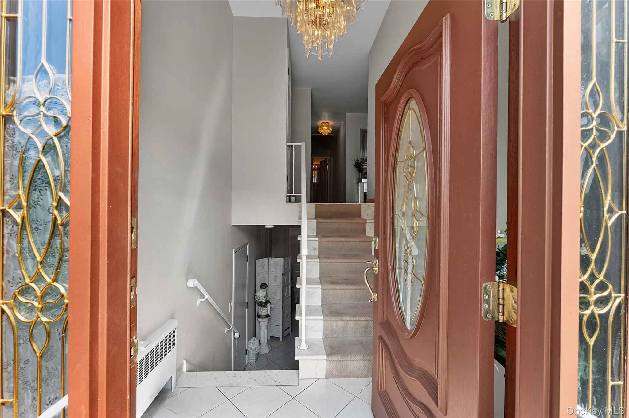 Entry foyer with tiled flooring and a multi-level staircase featuring white risers and handrails Entry foyer with tiled flooring and a multi-level staircase featuring white risers and handrails
