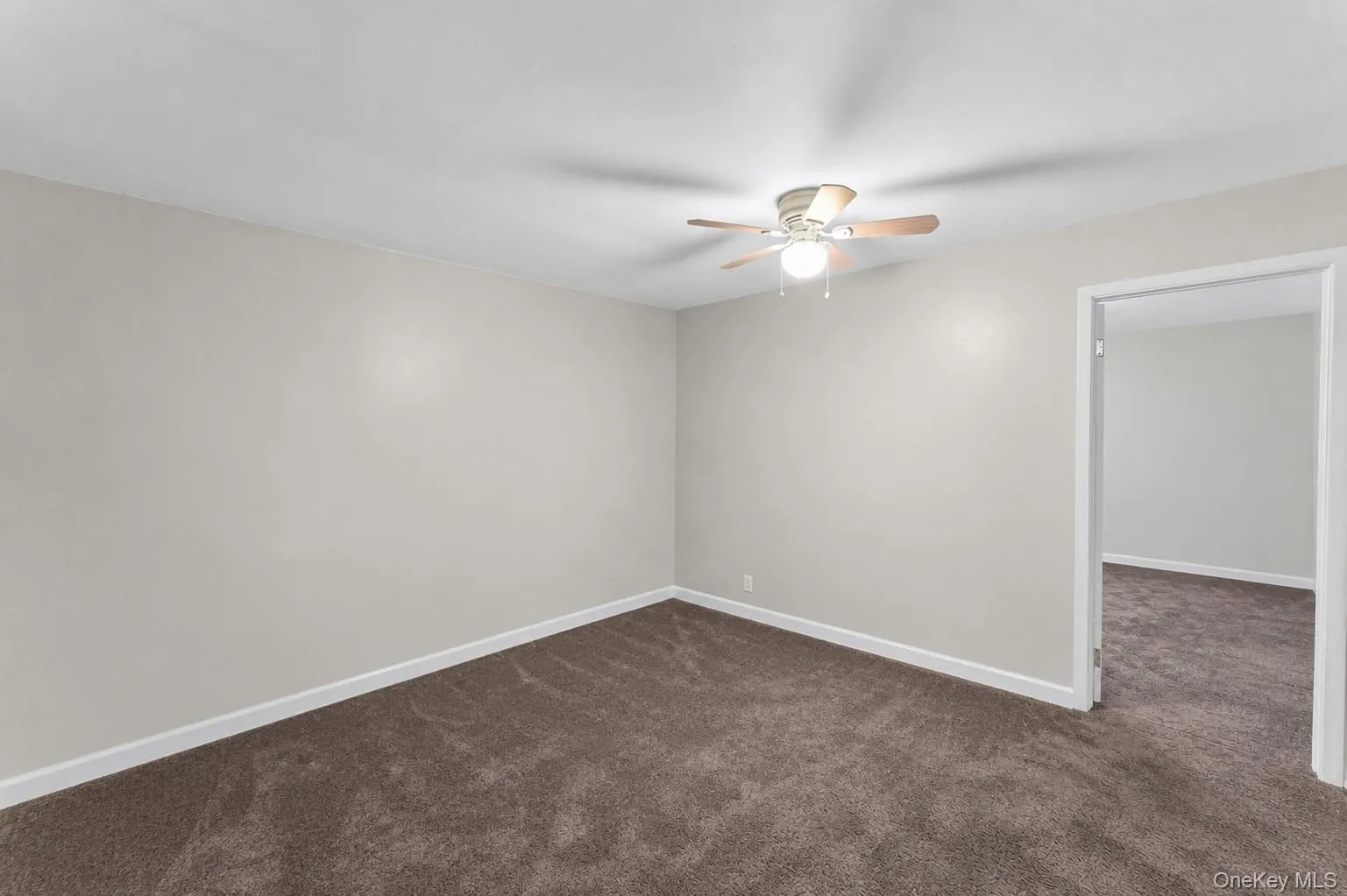 Spacious room featuring neutral wall paint, brown carpeting, and a ceiling fan with light fixture Spacious room featuring neutral wall paint, brown carpeting, and a ceiling fan with light fixture