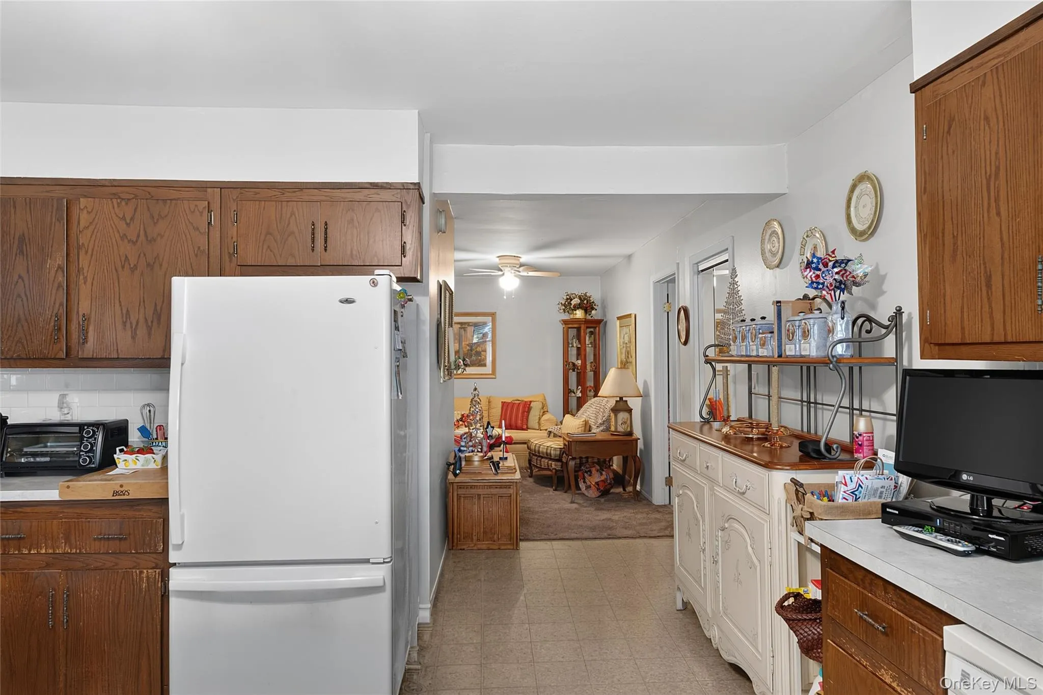 Galley kitchen featuring wood-finish cabinetry, white appliances, and a tiled floor Galley kitchen featuring wood-finish cabinetry, white appliances, and a tiled floor