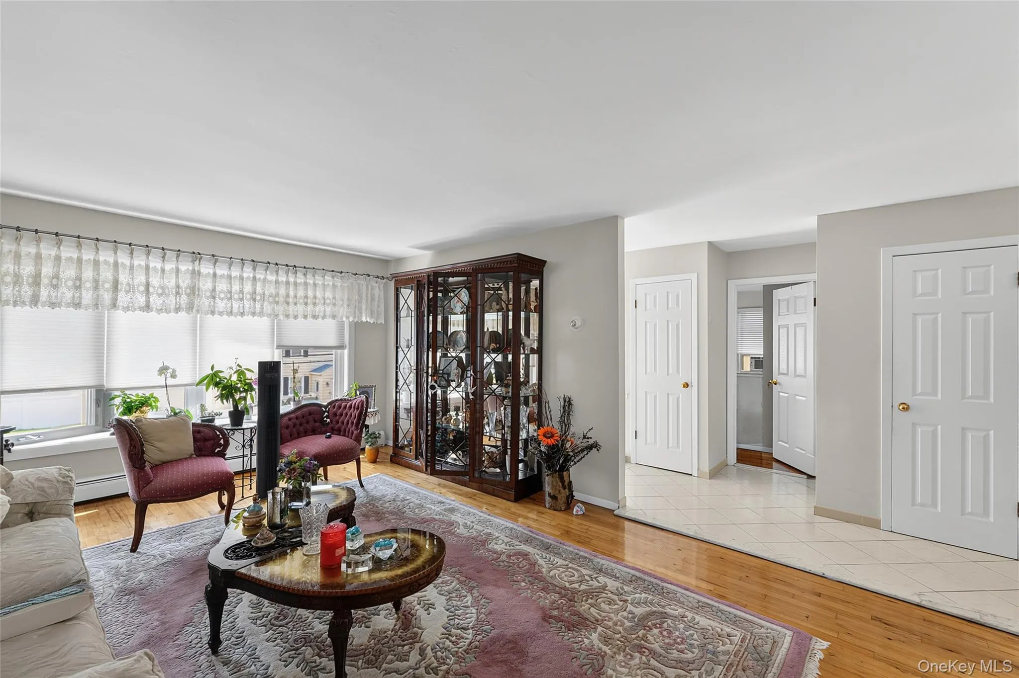 Hardwood flooring extends throughout the living area, complemented by a large window with roller shades Hardwood flooring extends throughout the living area, complemented by a large window with roller shades