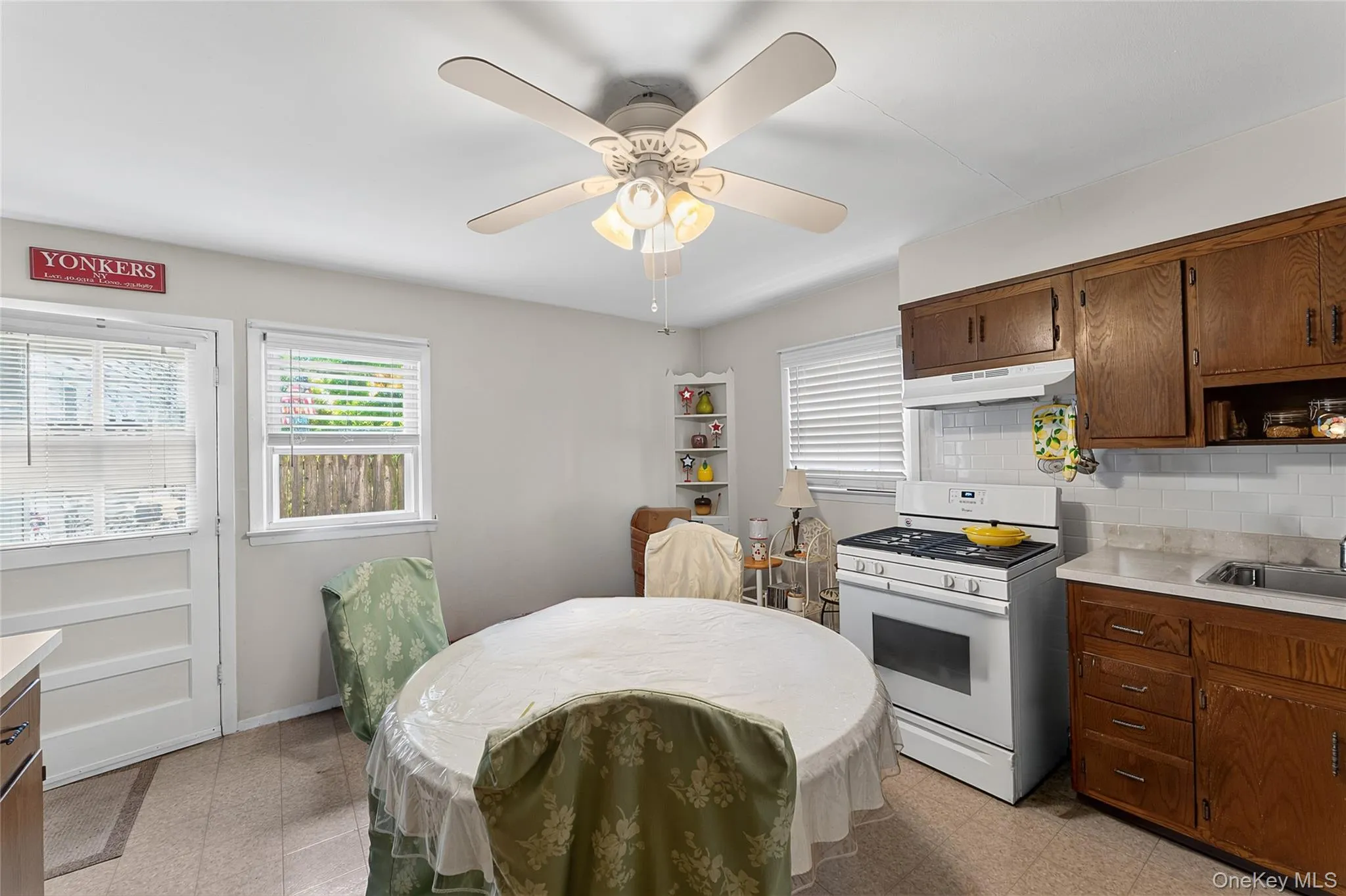 Eat-in kitchen featuring wood cabinetry, a white gas range with overhead ventilation, and a white subway tile backsplash Eat-in kitchen featuring wood cabinetry, a white gas range with overhead ventilation, and a white subway tile backsplash