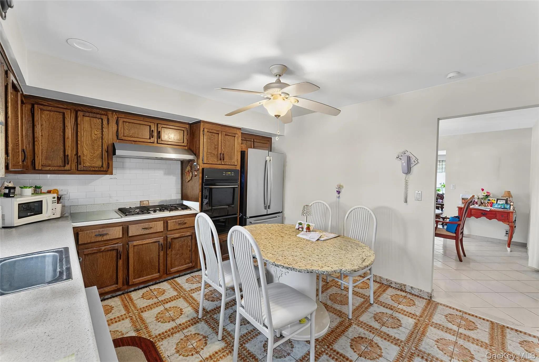 Kitchen featuring wood cabinetry, white subway tile backsplash, and patterned floor tile Kitchen featuring wood cabinetry, white subway tile backsplash, and patterned floor tile