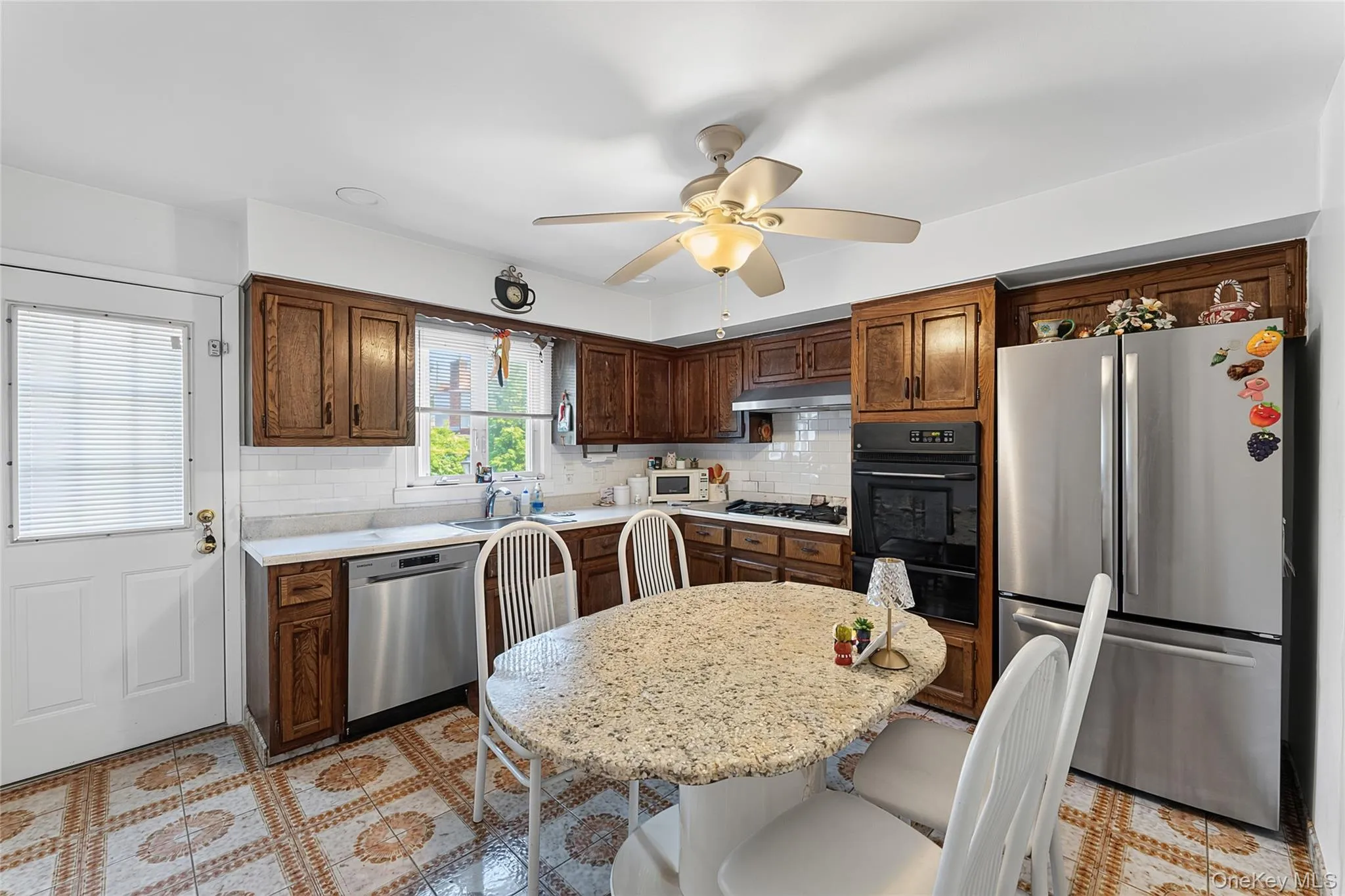 Kitchen featuring wood cabinetry, white subway tile backsplash, and light-toned countertops Kitchen featuring wood cabinetry, white subway tile backsplash, and light-toned countertops