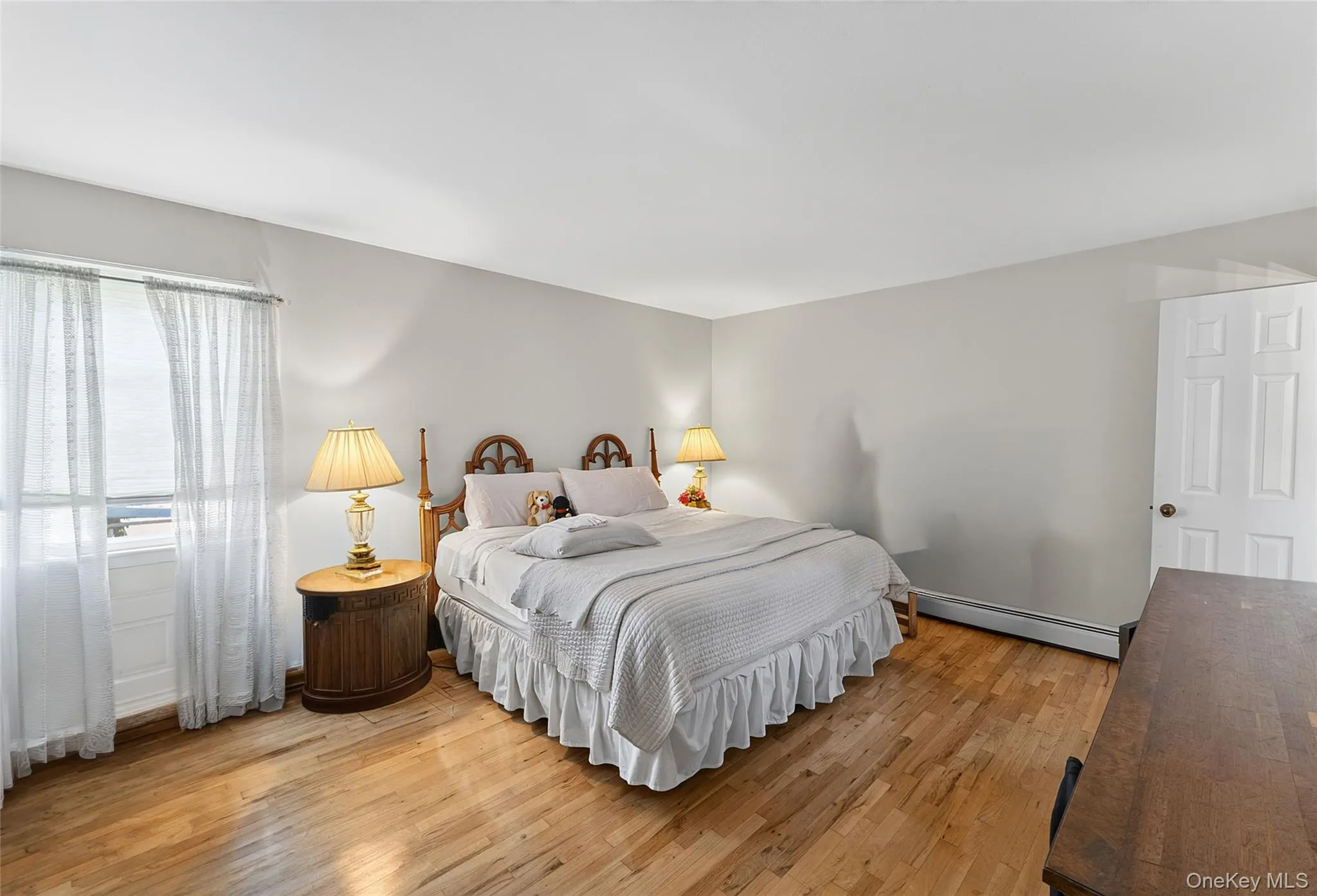 Room featuring wood-finish flooring, a full-height window, light-toned walls, and a white paneled door Room featuring wood-finish flooring, a full-height window, light-toned walls, and a white paneled door