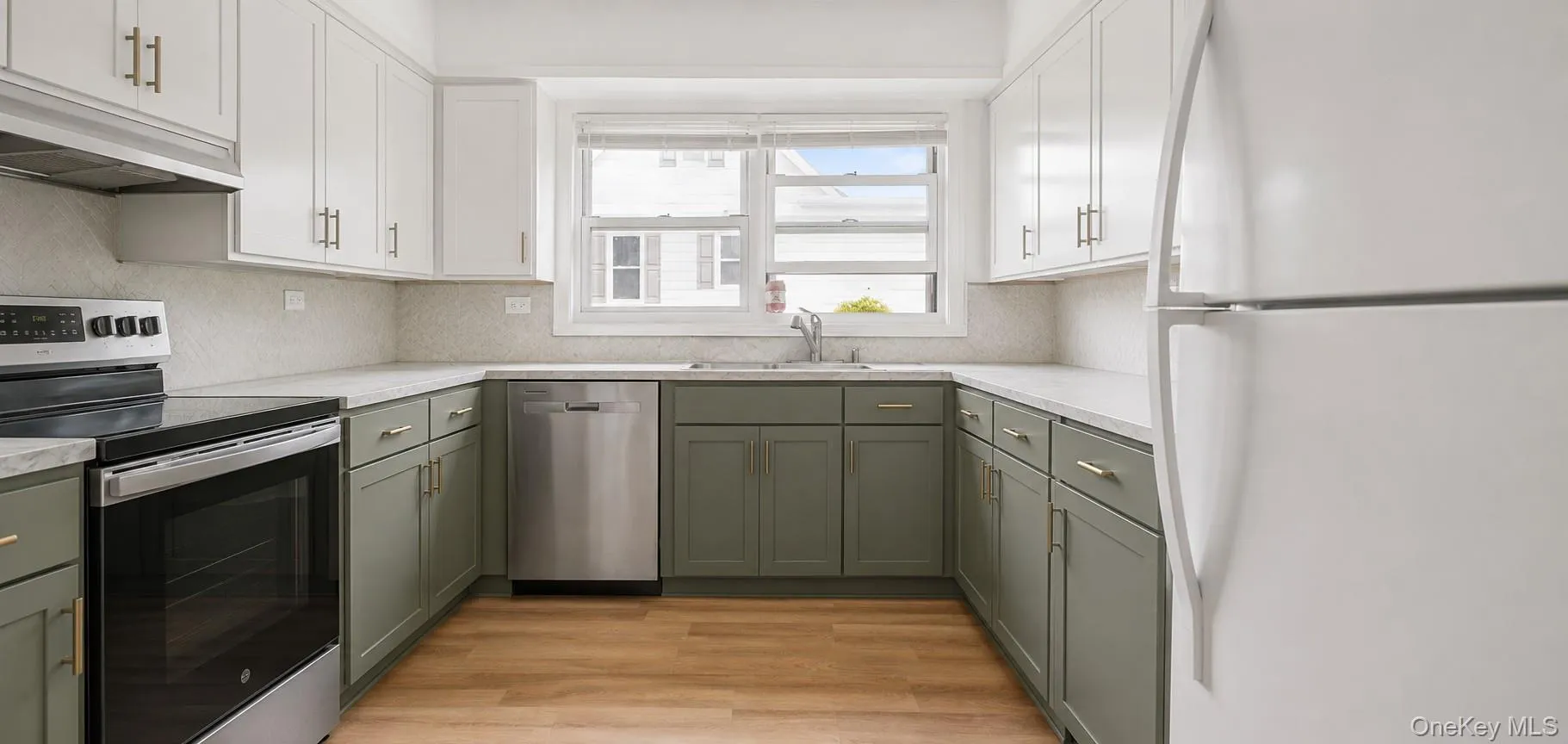 U-shaped kitchen featuring two-tone cabinetry with gold-tone hardware, white countertops, and wood-finish flooring U-shaped kitchen featuring two-tone cabinetry with gold-tone hardware, white countertops, and wood-finish flooring
