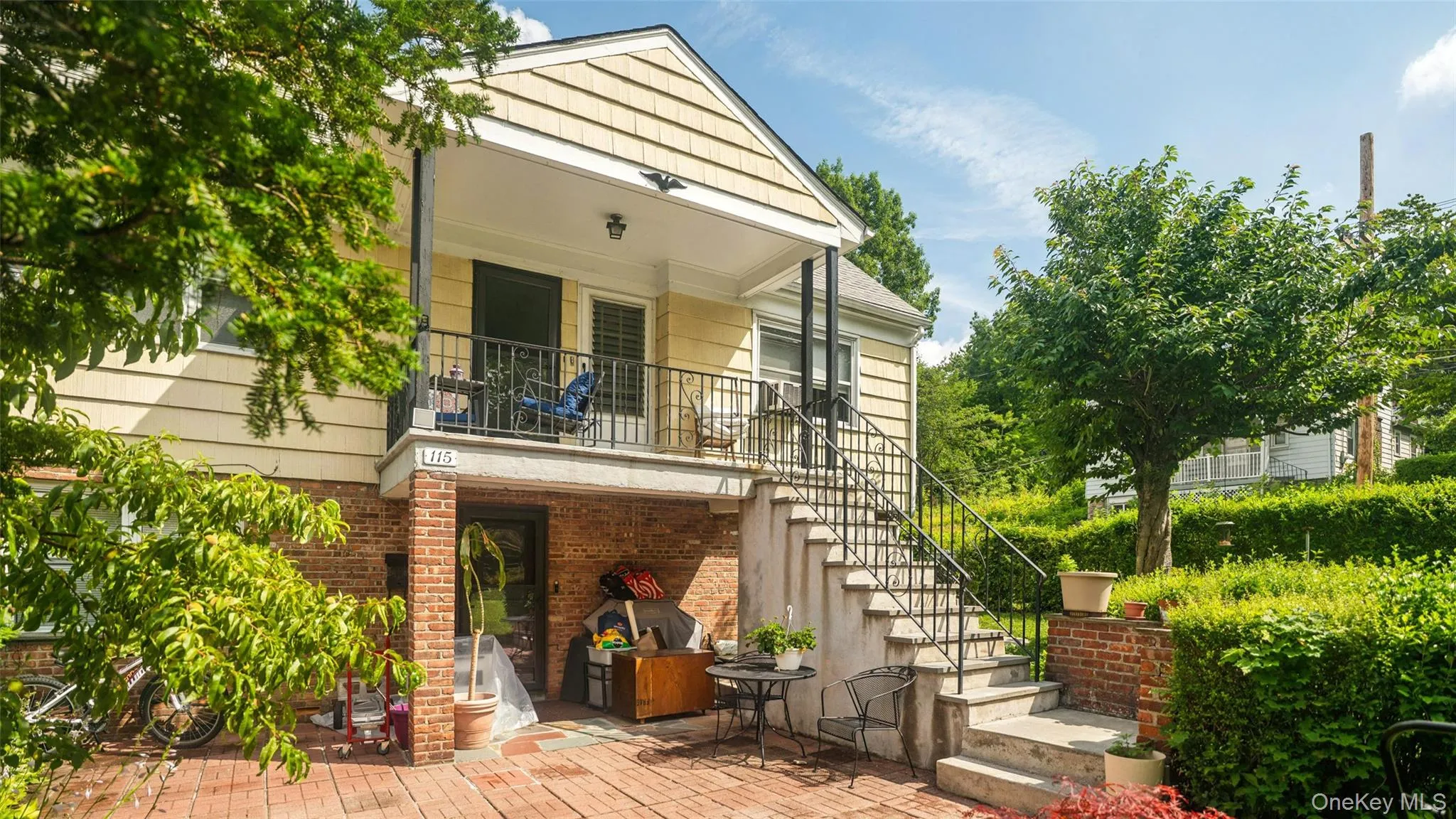 Rear exterior featuring two levels of outdoor living, a brick patio, and a staircase Rear exterior featuring two levels of outdoor living, a brick patio, and a staircase
