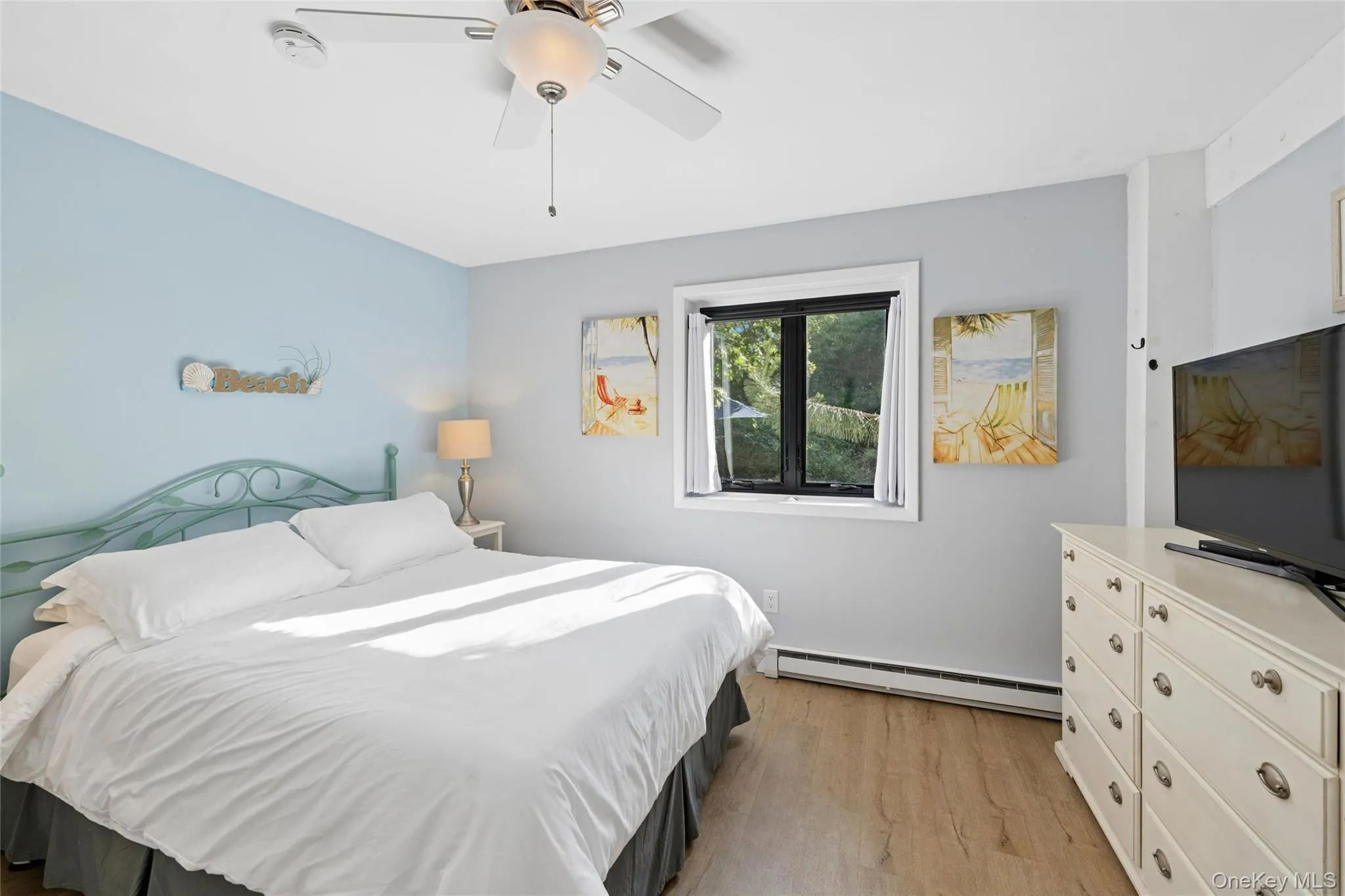 Bedroom featuring wood-finish flooring, a ceiling fan with integrated lighting, and a single window with a dark frame Bedroom featuring wood-finish flooring, a ceiling fan with integrated lighting, and a single window with a dark frame