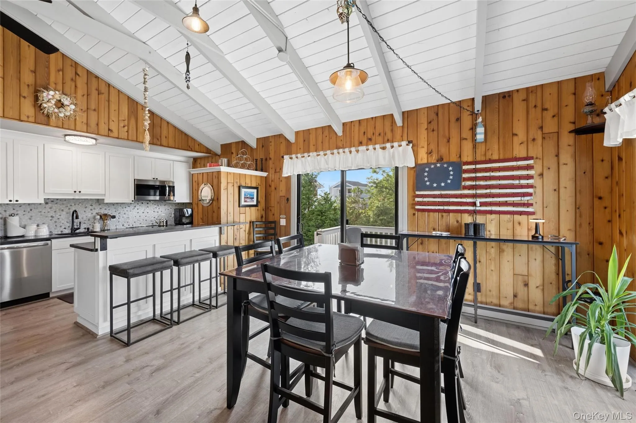 Vaulted wood-paneled ceiling with exposed beams, white cabinetry, stainless steel appliances, and wood-finish flooring Vaulted wood-paneled ceiling with exposed beams, white cabinetry, stainless steel appliances, and wood-finish flooring