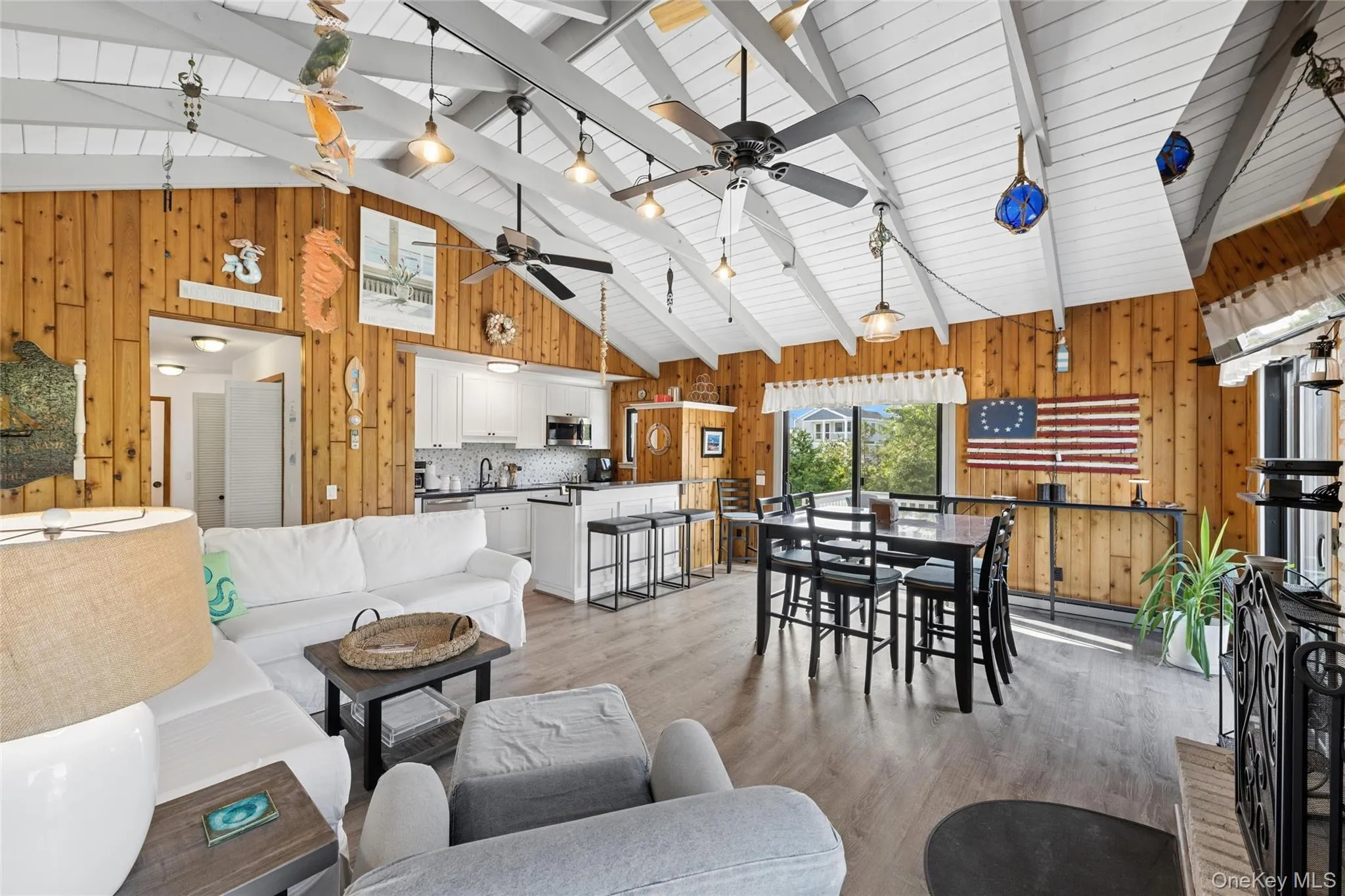 Vaulted white wood beam ceiling throughout an open concept living area featuring wood-finish flooring Vaulted white wood beam ceiling throughout an open concept living area featuring wood-finish flooring