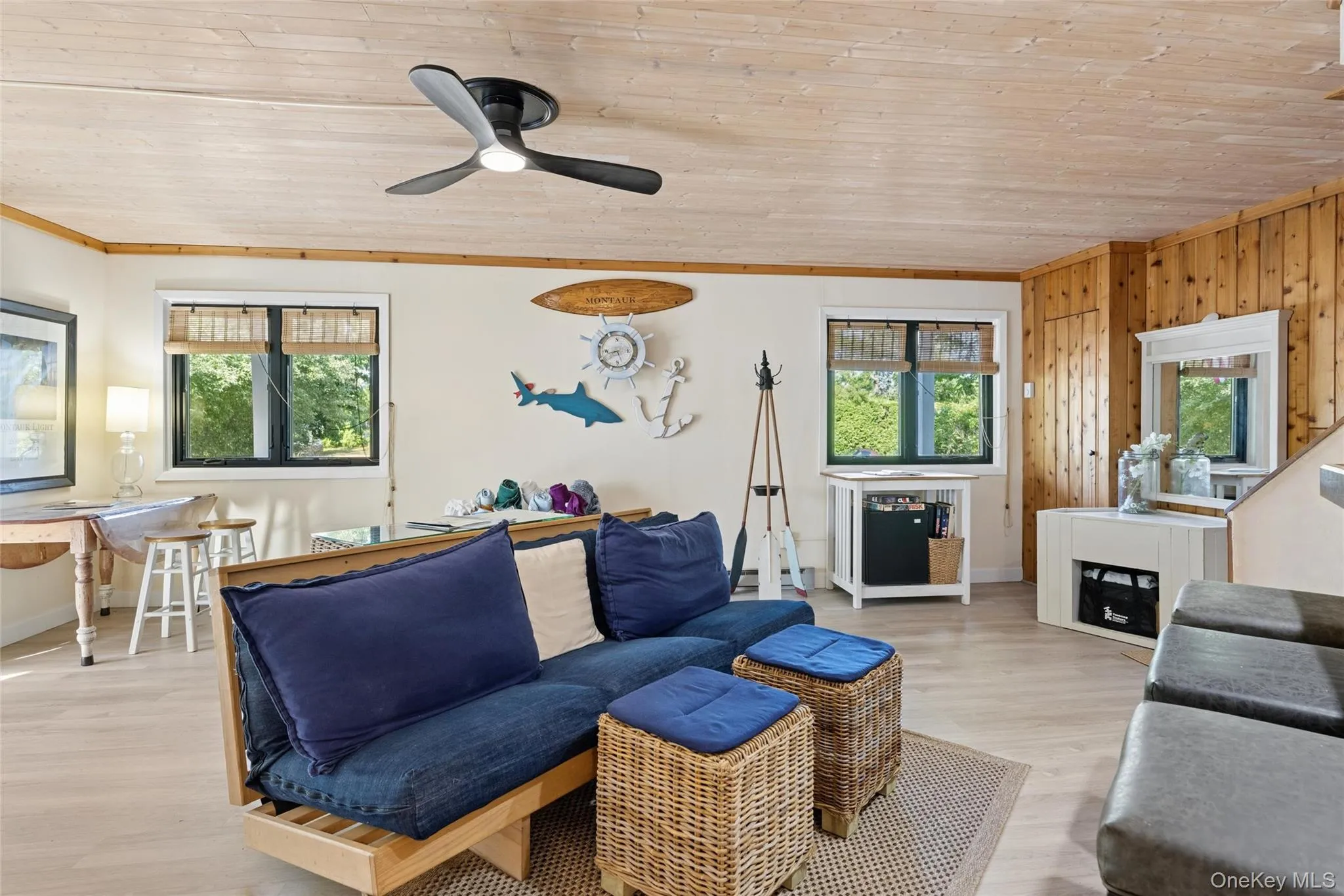 Living area with wood-finish flooring, a light wood-paneled ceiling, and a black ceiling fan Living area with wood-finish flooring, a light wood-paneled ceiling, and a black ceiling fan