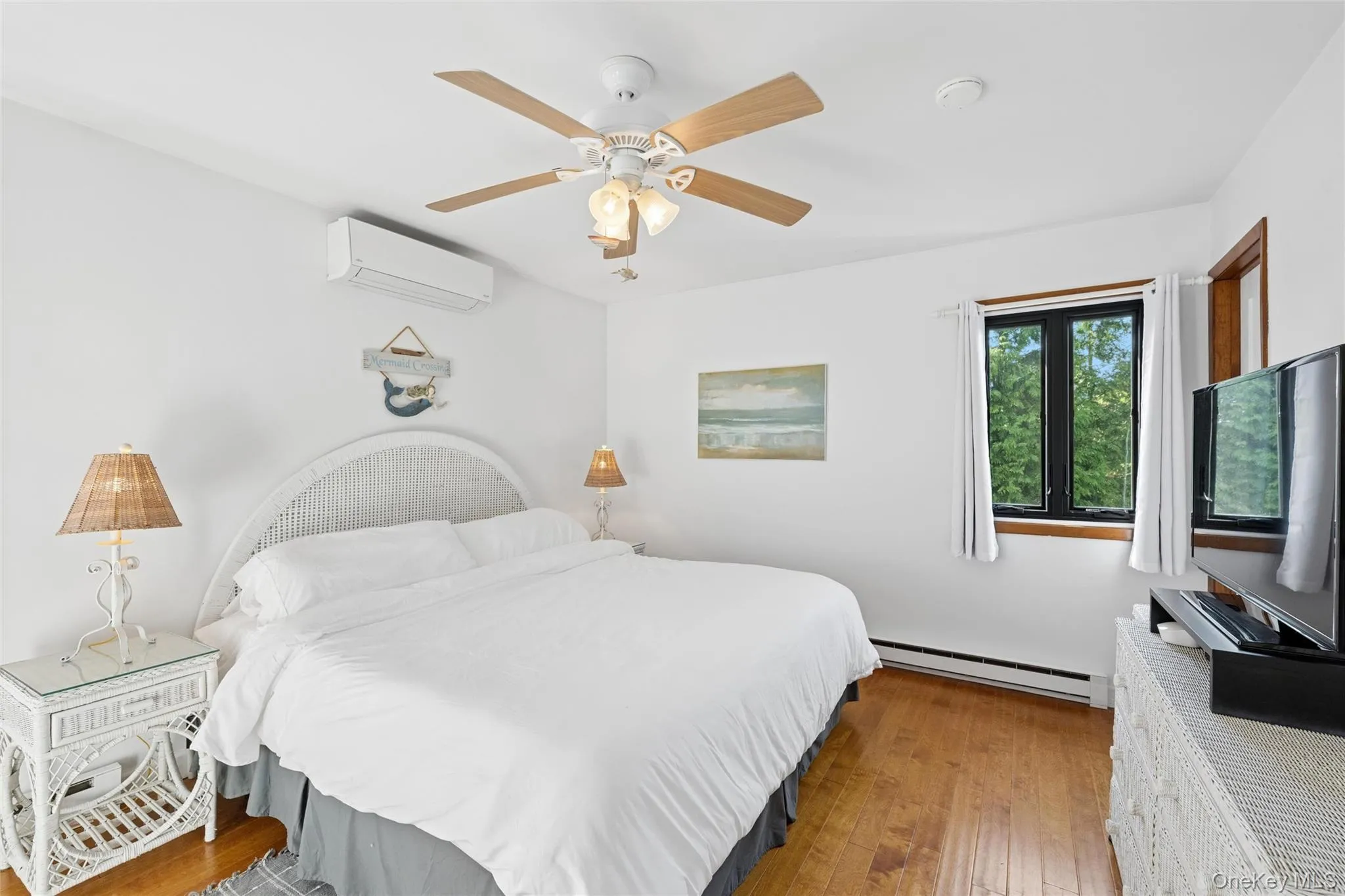 Bedroom featuring wood-finish flooring, white walls, and a ceiling fan with integrated lighting Bedroom featuring wood-finish flooring, white walls, and a ceiling fan with integrated lighting
