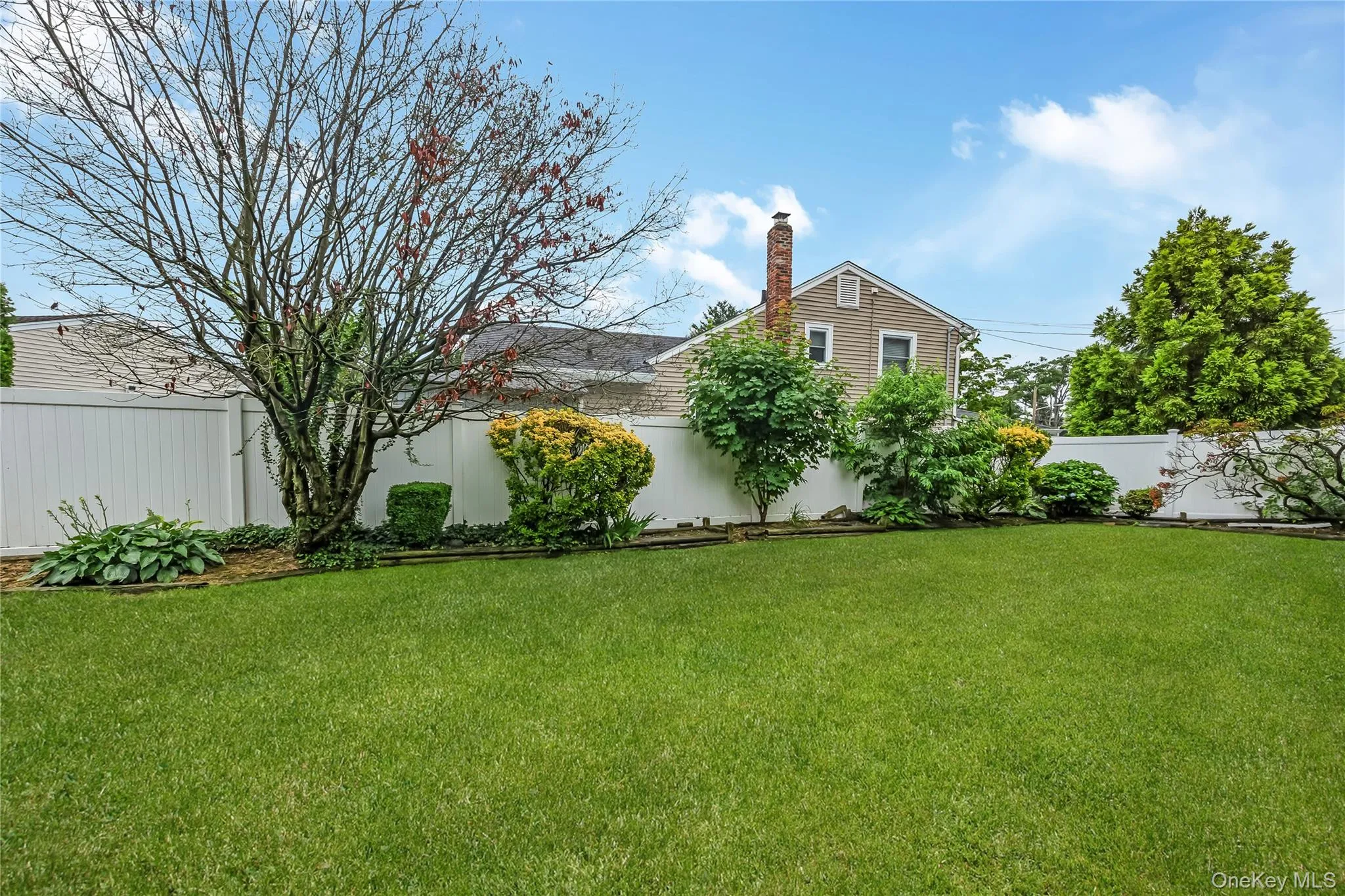 Yard featuring a storage shed, mature trees, and a white privacy fence Yard featuring a storage shed, mature trees, and a white privacy fence
