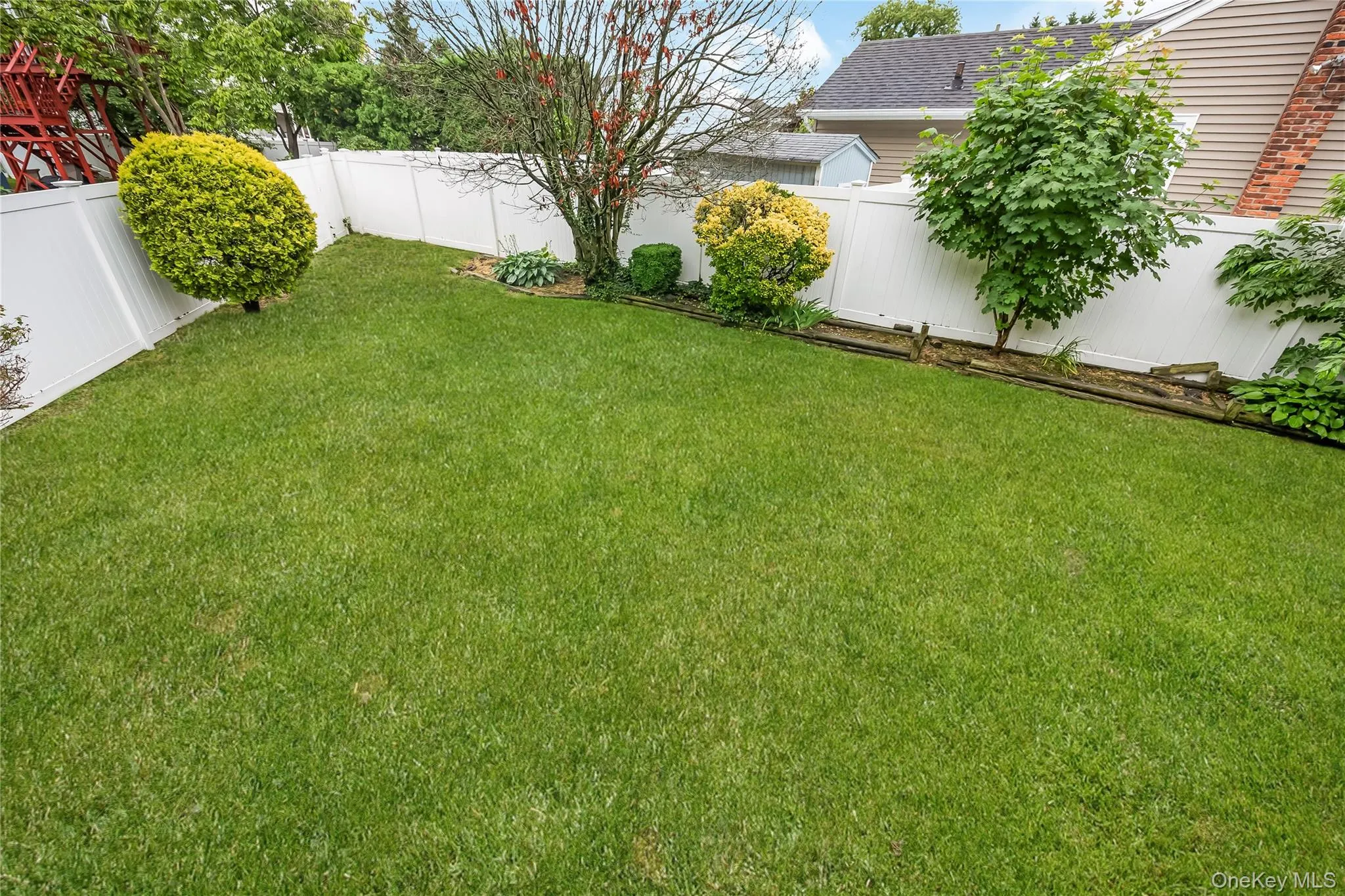 Yard featuring a storage shed, mature trees, and a white privacy fence Yard featuring a storage shed, mature trees, and a white privacy fence