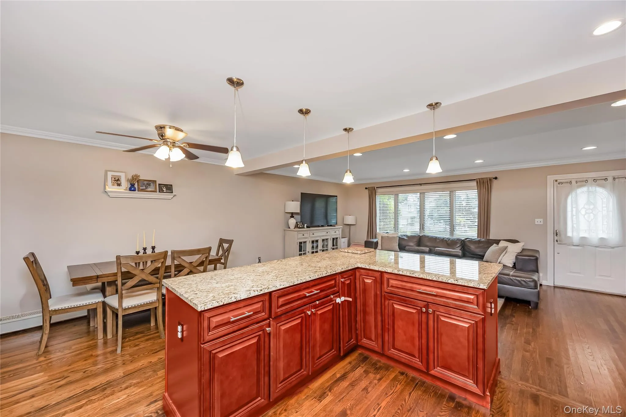Kitchen with open access to the Dining room and Living room featuring wood-finish cabinetry, stainless steel appliances, granite-style countertops, and a tile backsplash Kitchen with open access to the Dining room and Living room featuring wood-finish cabinetry, stainless steel appliances, granite-style countertops, and a tile backsplash