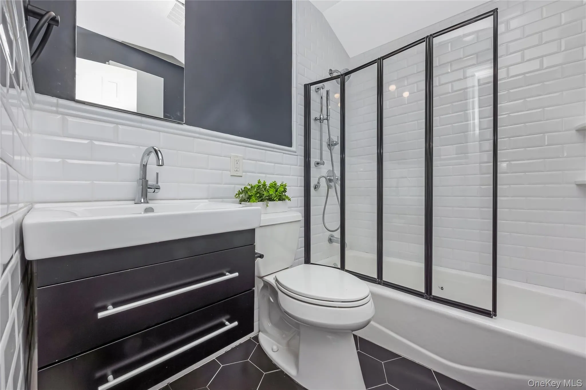 Bathroom featuring a black hexagon tile floor, white subway tile walls, and a contemporary floating vanity with an integrated sink Bathroom featuring a black hexagon tile floor, white subway tile walls, and a contemporary floating vanity with an integrated sink