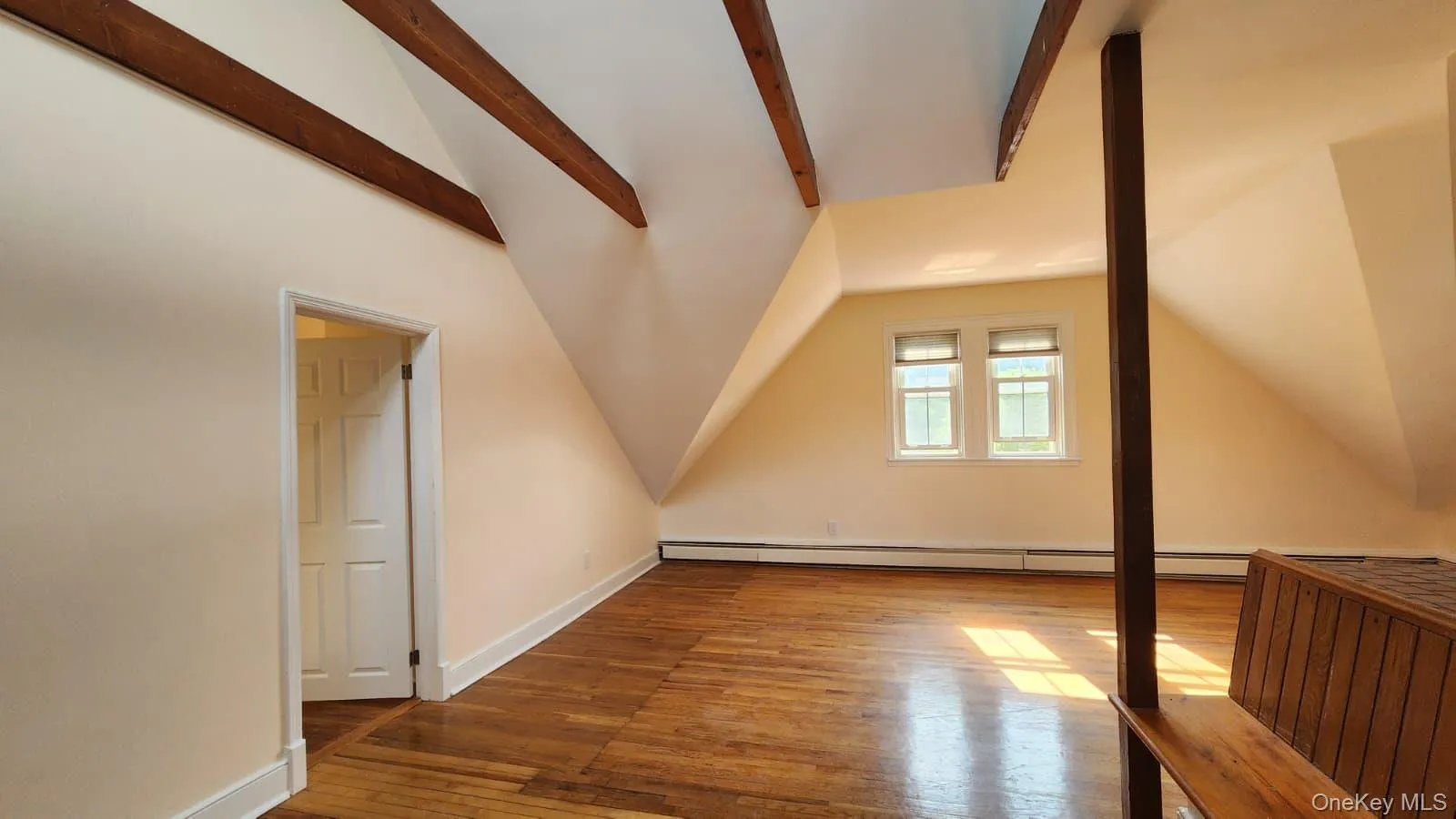 Spacious living room featuring exposed wood beams, sloped ceilings, wood-finish flooring, plenty of windows for ample light Spacious living room featuring exposed wood beams, sloped ceilings, wood-finish flooring, plenty of windows for ample light