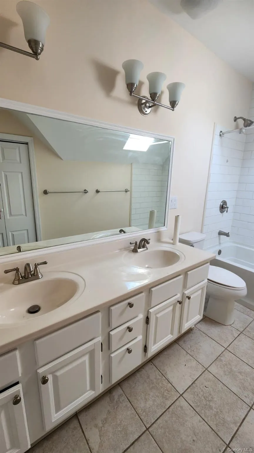 Double vanity with integrated sinks, white cabinetry, and brushed nickel hardware; linen closet Double vanity with integrated sinks, white cabinetry, and brushed nickel hardware; linen closet