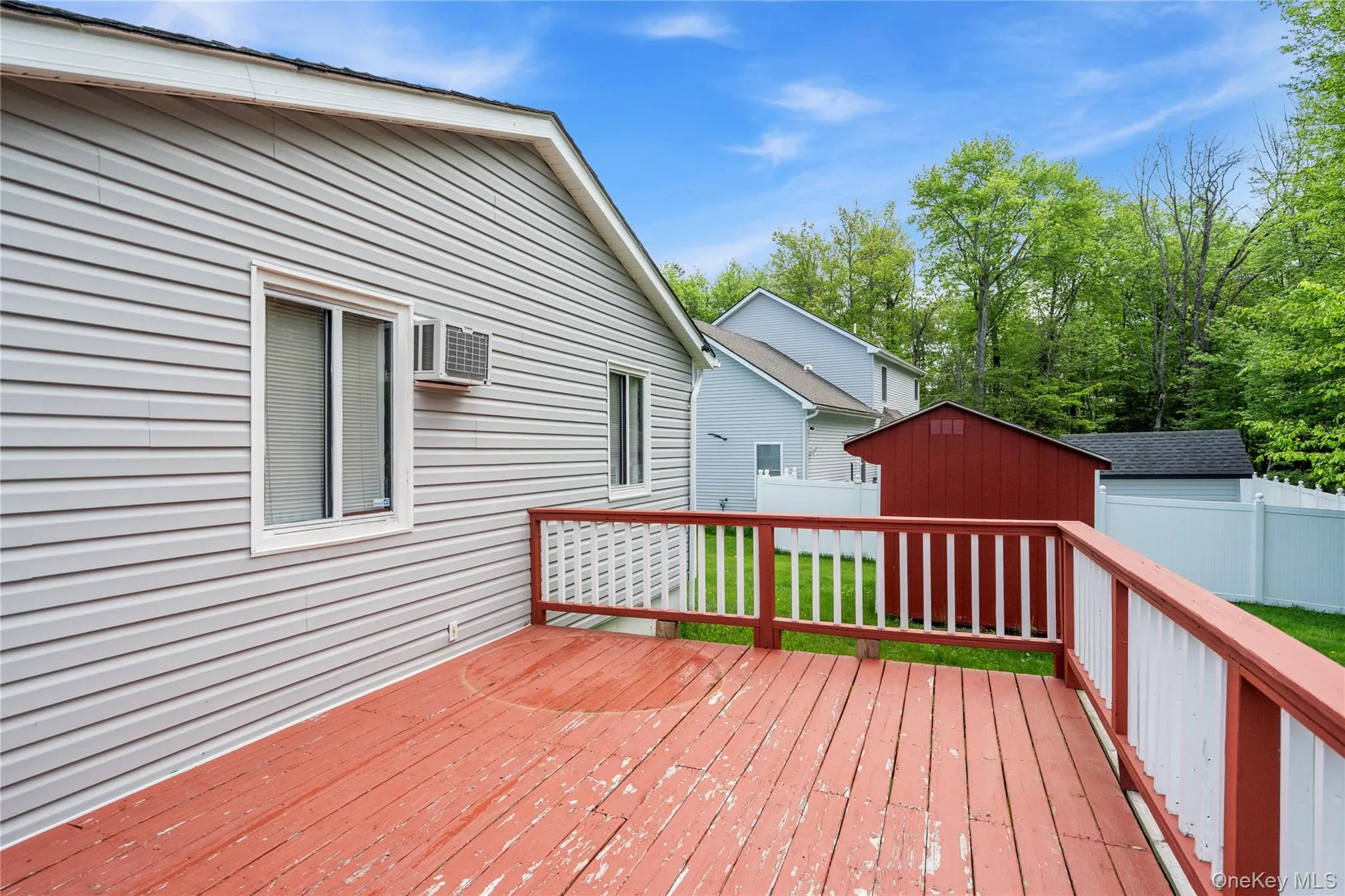 Wooden deck featuring a shed, fence, an outdoor structure, and a wall unit AC Wooden deck featuring a shed, fence, an outdoor structure, and a wall unit AC