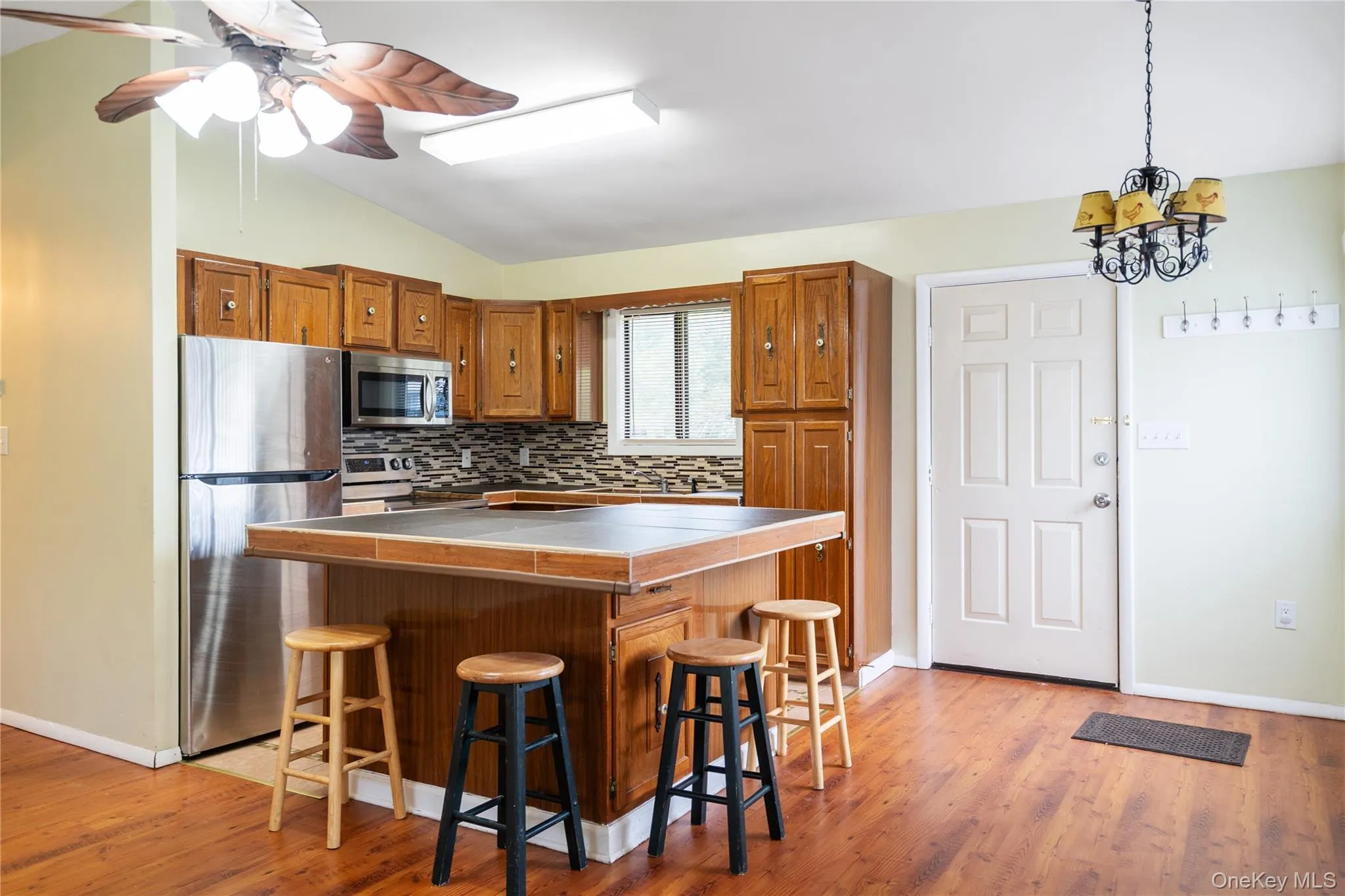 Kitchen with appliances with stainless steel finishes, brown cabinets, lofted ceiling, a center island, and a breakfast bar Kitchen with appliances with stainless steel finishes, brown cabinets, lofted ceiling, a center island, and a breakfast bar