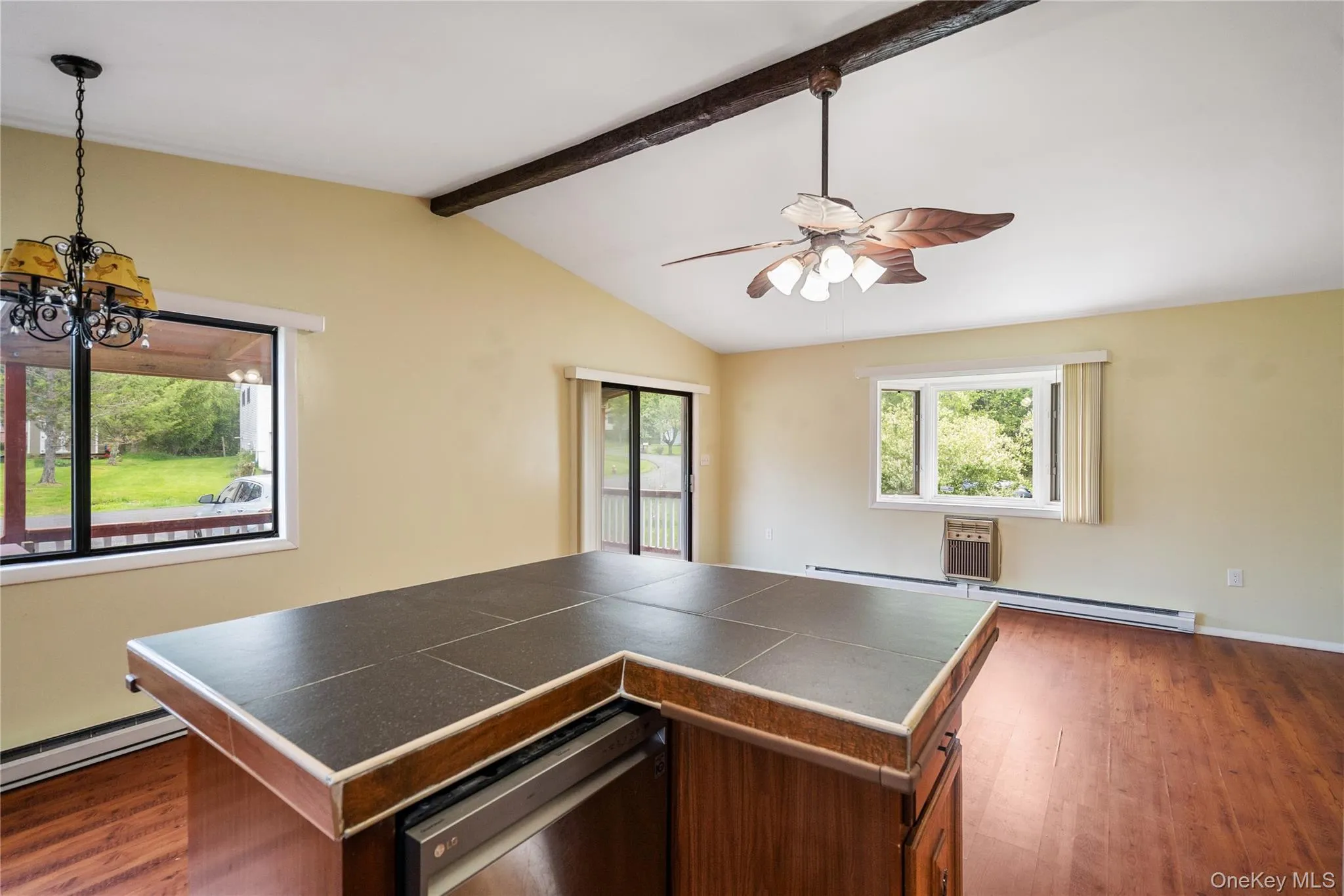 Kitchen featuring dark wood-style floors, a ceiling fan, a chandelier, and tile countertops Kitchen featuring dark wood-style floors, a ceiling fan, a chandelier, and tile countertops