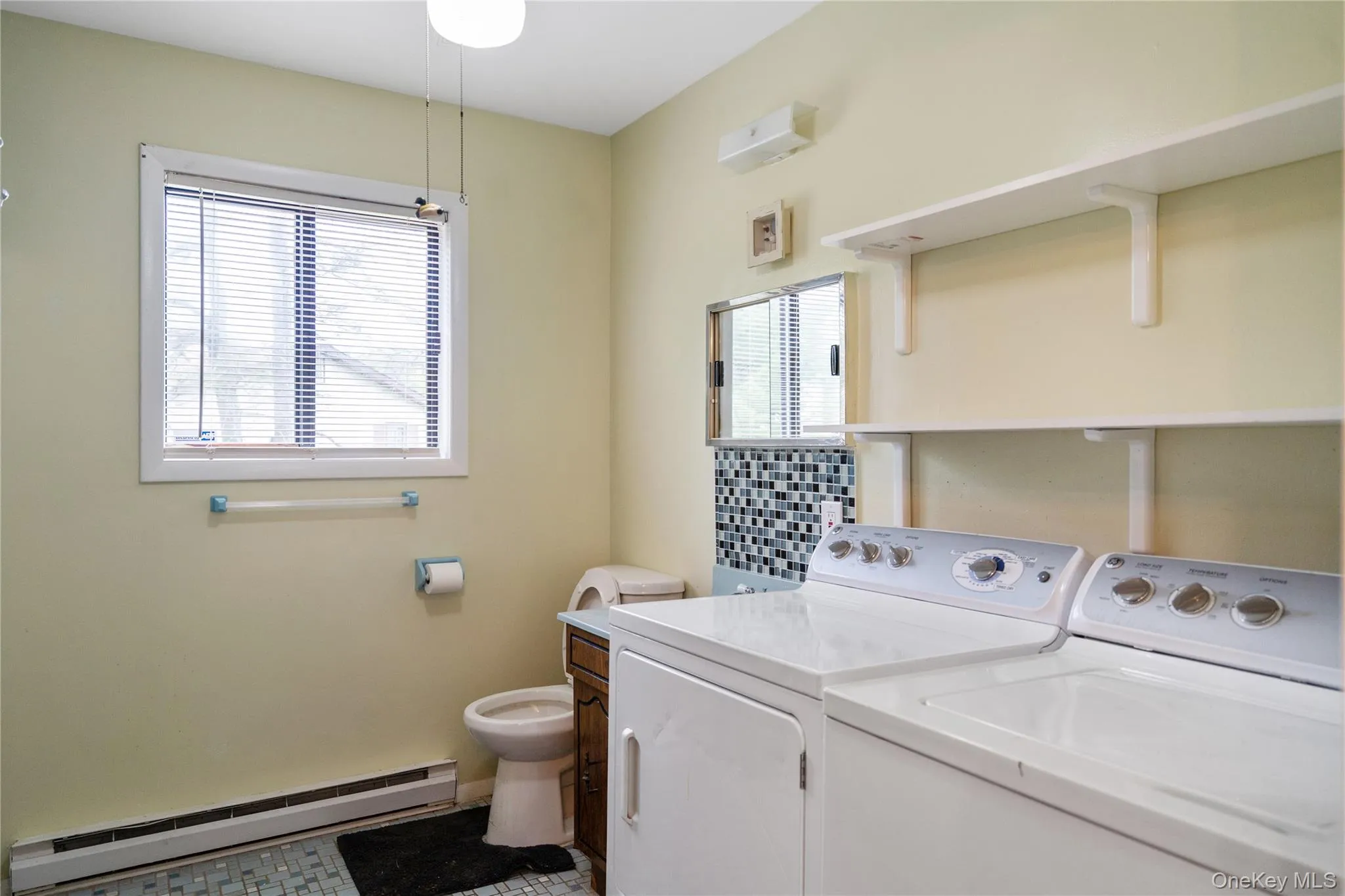 Clothes washing area featuring baseboard heating, washer and dryer, and baseboards Clothes washing area featuring baseboard heating, washer and dryer, and baseboards