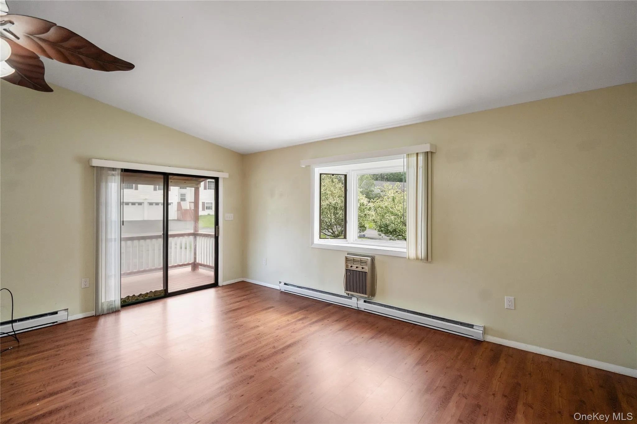 Spare room featuring a baseboard heating unit, a ceiling fan, wood finished floors, and lofted ceiling Spare room featuring a baseboard heating unit, a ceiling fan, wood finished floors, and lofted ceiling