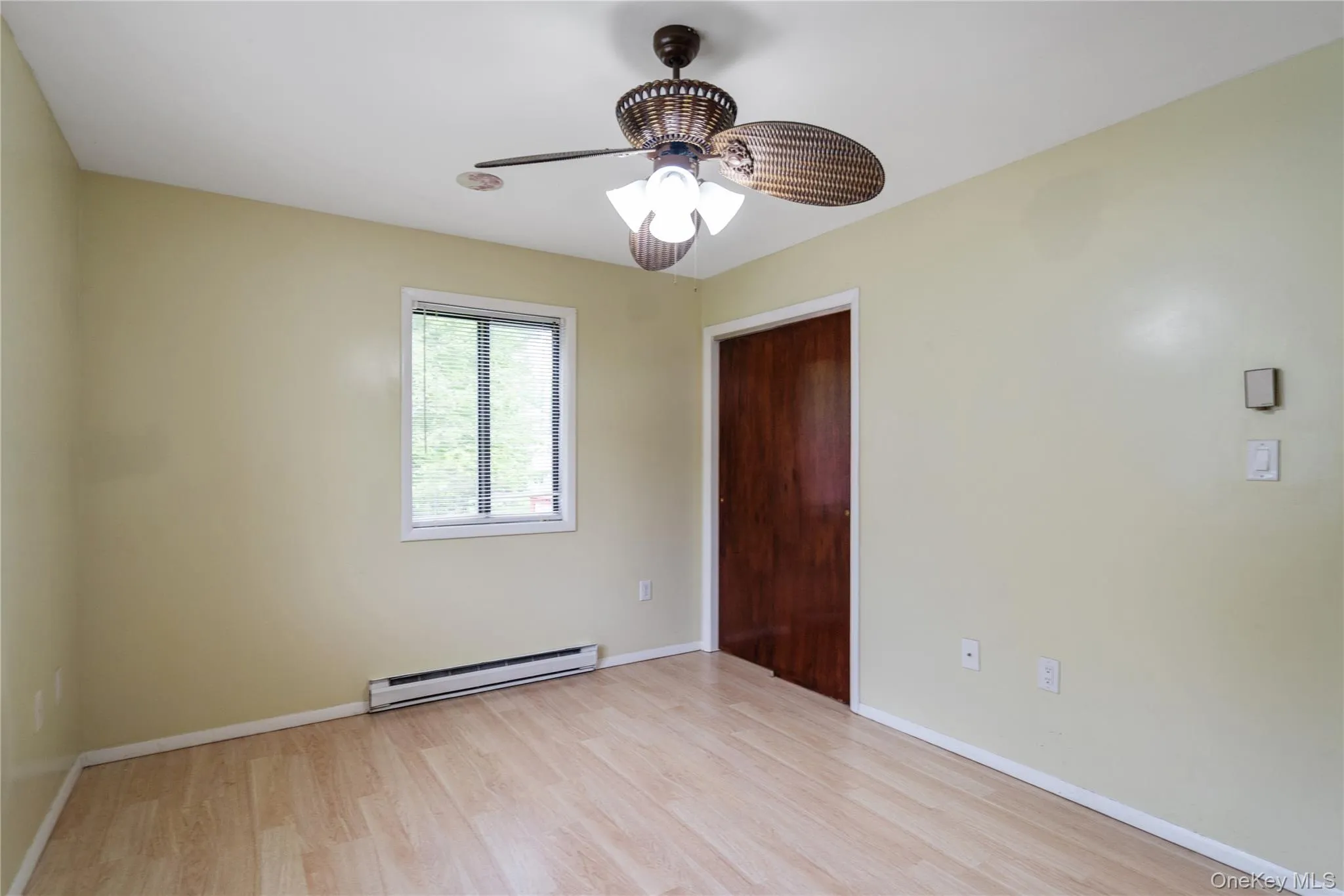 Spare room featuring a baseboard heating unit, light wood finished floors, a ceiling fan, and baseboards Spare room featuring a baseboard heating unit, light wood finished floors, a ceiling fan, and baseboards