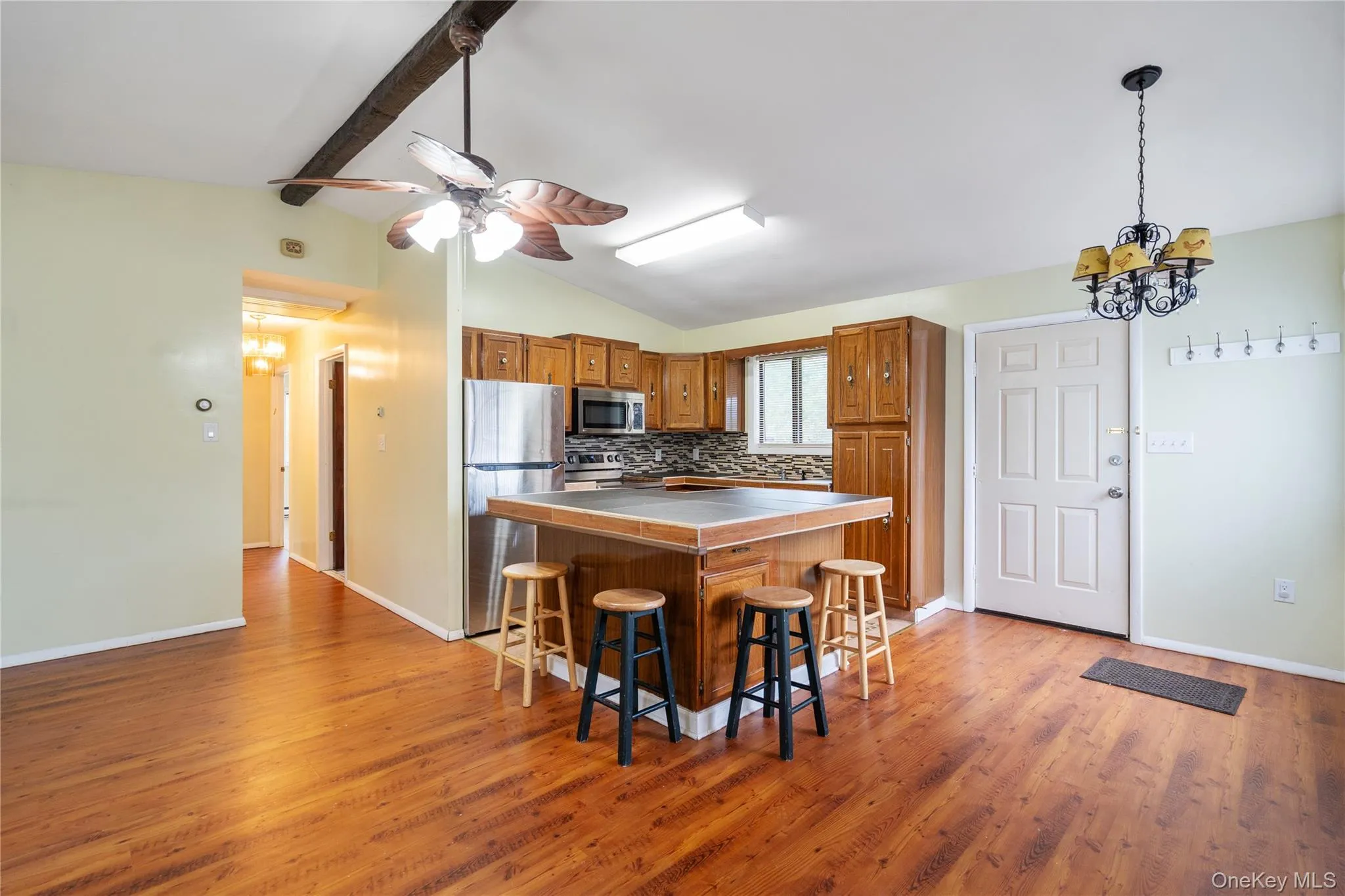 Kitchen with stainless steel appliances, brown cabinets, a kitchen breakfast bar, a chandelier, and light wood-style flooring Kitchen with stainless steel appliances, brown cabinets, a kitchen breakfast bar, a chandelier, and light wood-style flooring