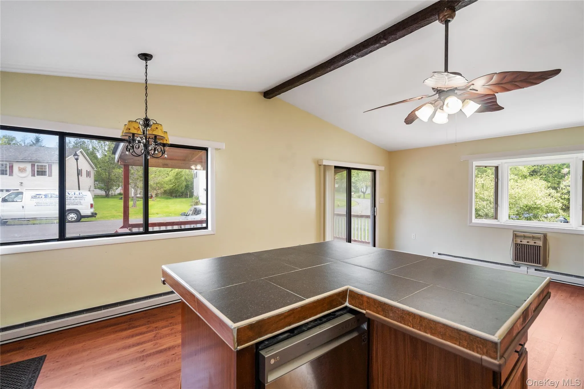 Kitchen featuring wood finished floors, stainless steel dishwasher, a ceiling fan, a chandelier, and a baseboard radiator Kitchen featuring wood finished floors, stainless steel dishwasher, a ceiling fan, a chandelier, and a baseboard radiator