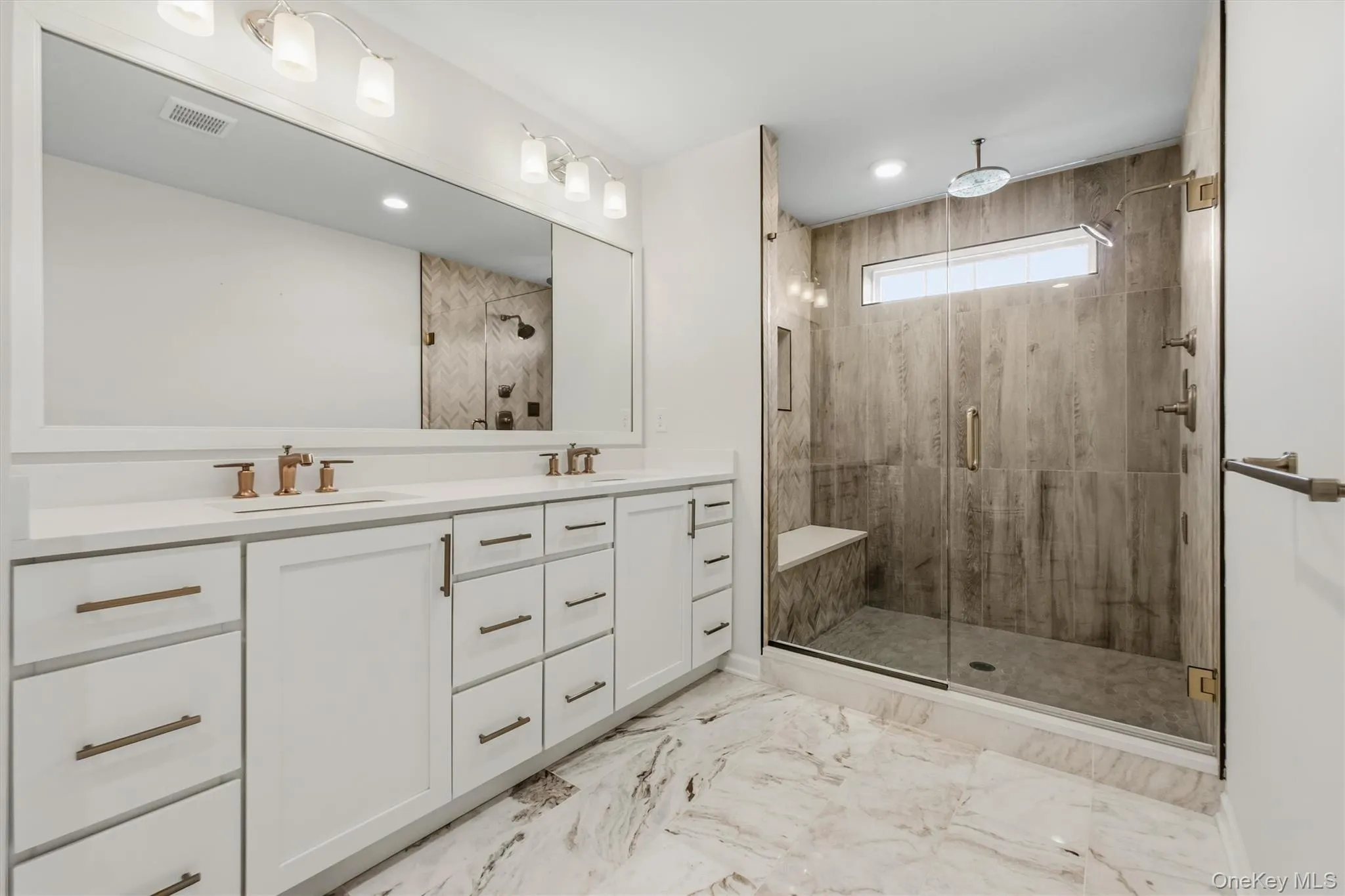 Master bathroom. Walk-in shower with a glass enclosure, dual shower heads, and an integrated bench. Dual vanity. Master bathroom. Walk-in shower with a glass enclosure, dual shower heads, and an integrated bench. Dual vanity.