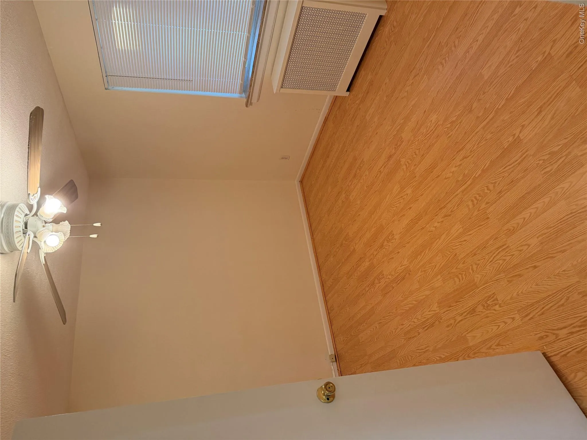 Room featuring wood-finish flooring, a ceiling fan with integrated lighting, a window with horizontal blinds, and a white radiator cover Room featuring wood-finish flooring, a ceiling fan with integrated lighting, a window with horizontal blinds, and a white radiator cover