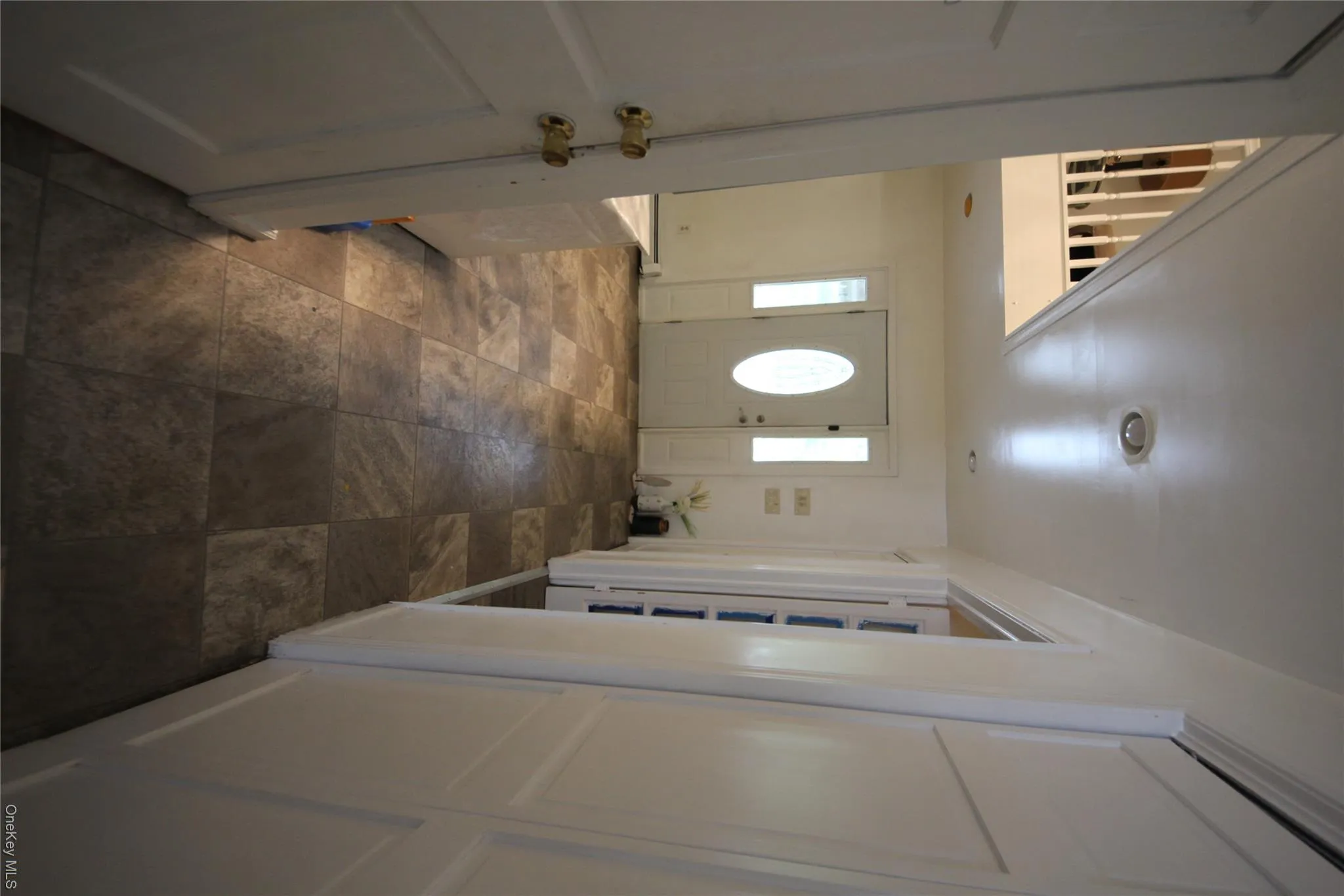 Entryway featuring a white oval-lite front door with sidelights, recessed lighting, and multi-toned square floor tiling Entryway featuring a white oval-lite front door with sidelights, recessed lighting, and multi-toned square floor tiling