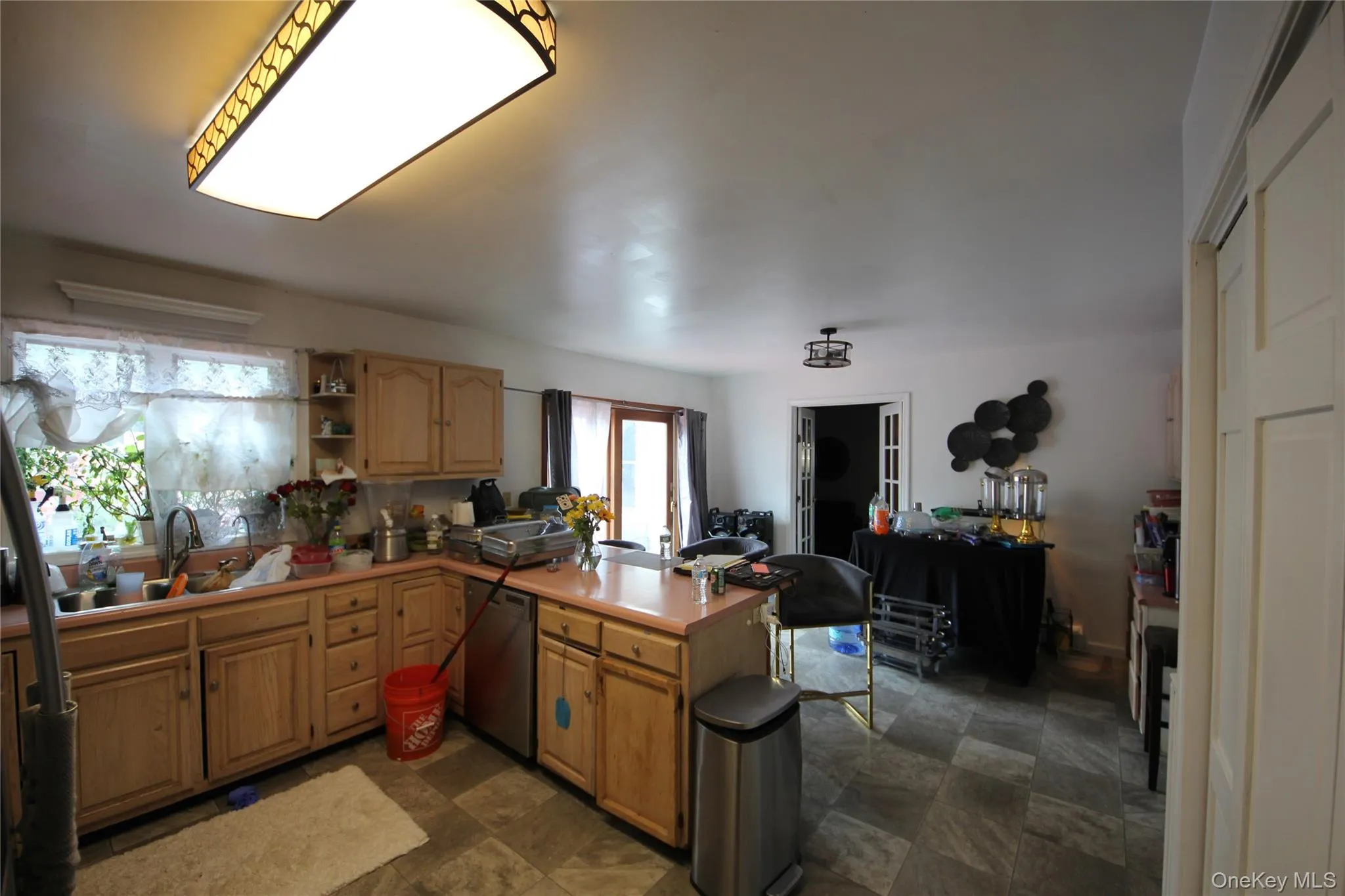 Kitchen featuring wood cabinetry, light pink countertops, and a stainless steel dishwasher Kitchen featuring wood cabinetry, light pink countertops, and a stainless steel dishwasher