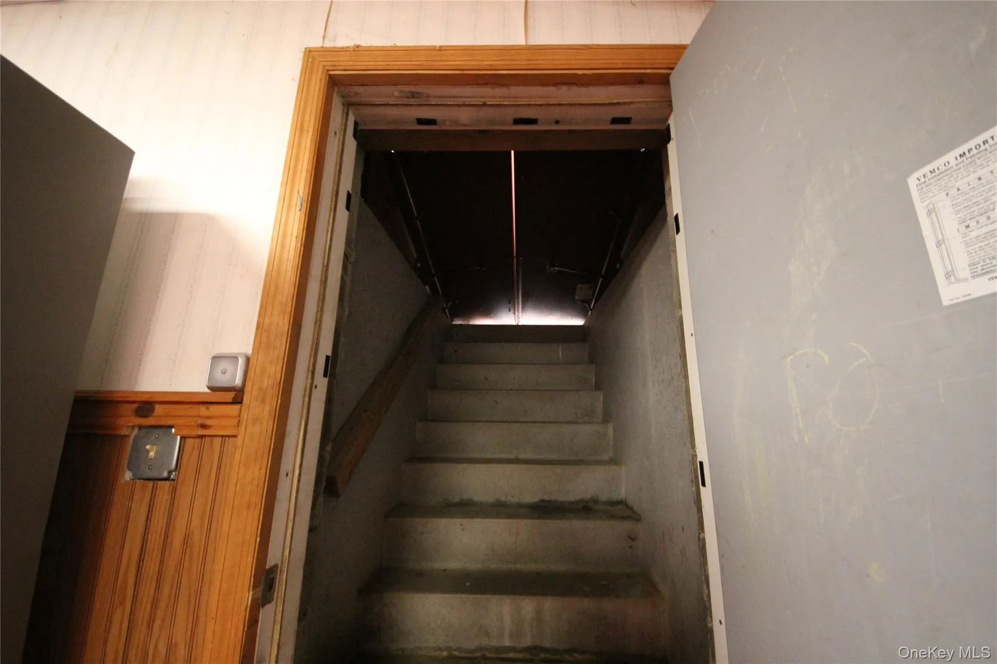 Concrete staircase with a wooden handrail and a light wood trim doorway Concrete staircase with a wooden handrail and a light wood trim doorway